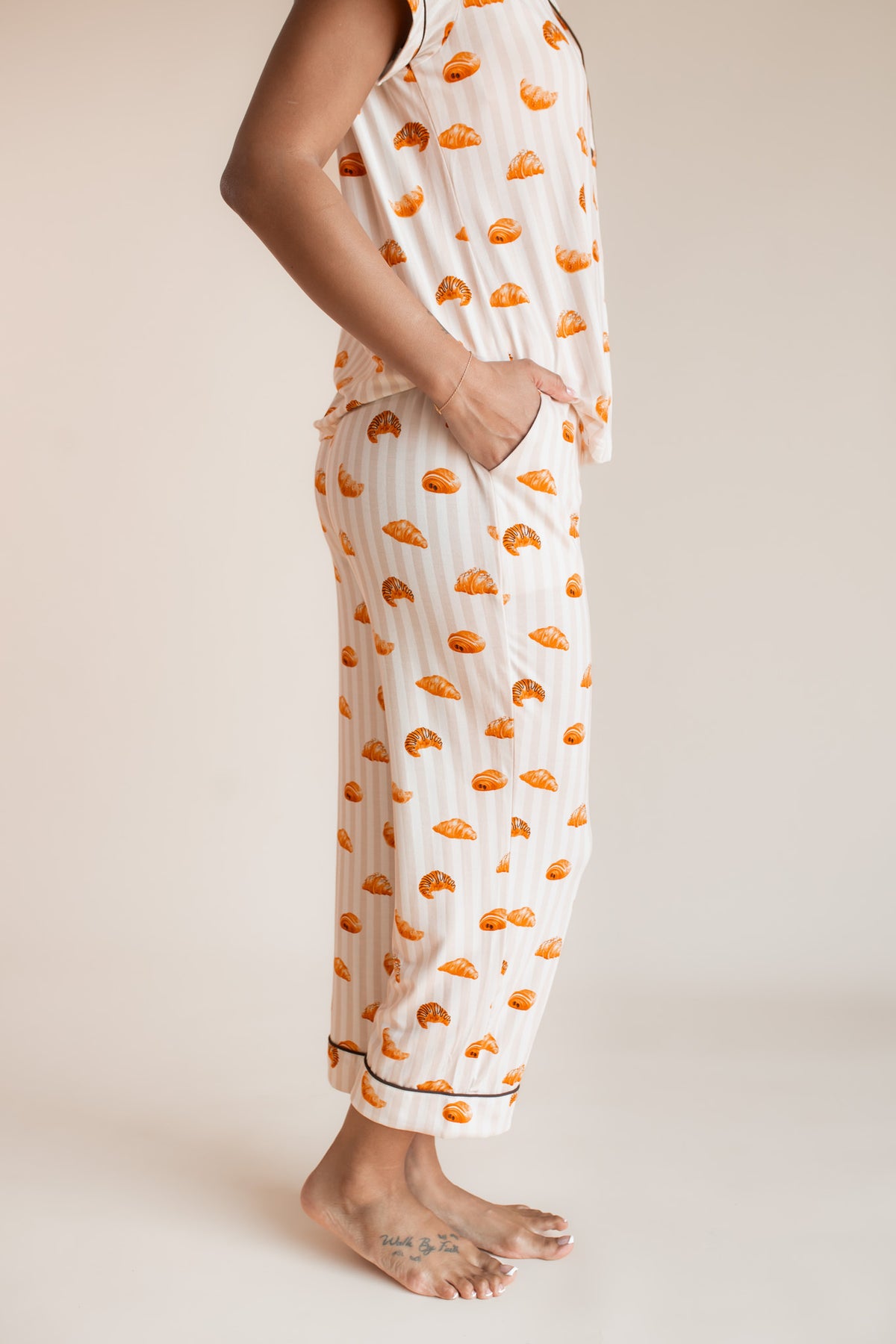 Model showcasing pajama pockets on Women's Short Sleeve Cropped Pajama Set with Croissant print on a beige background