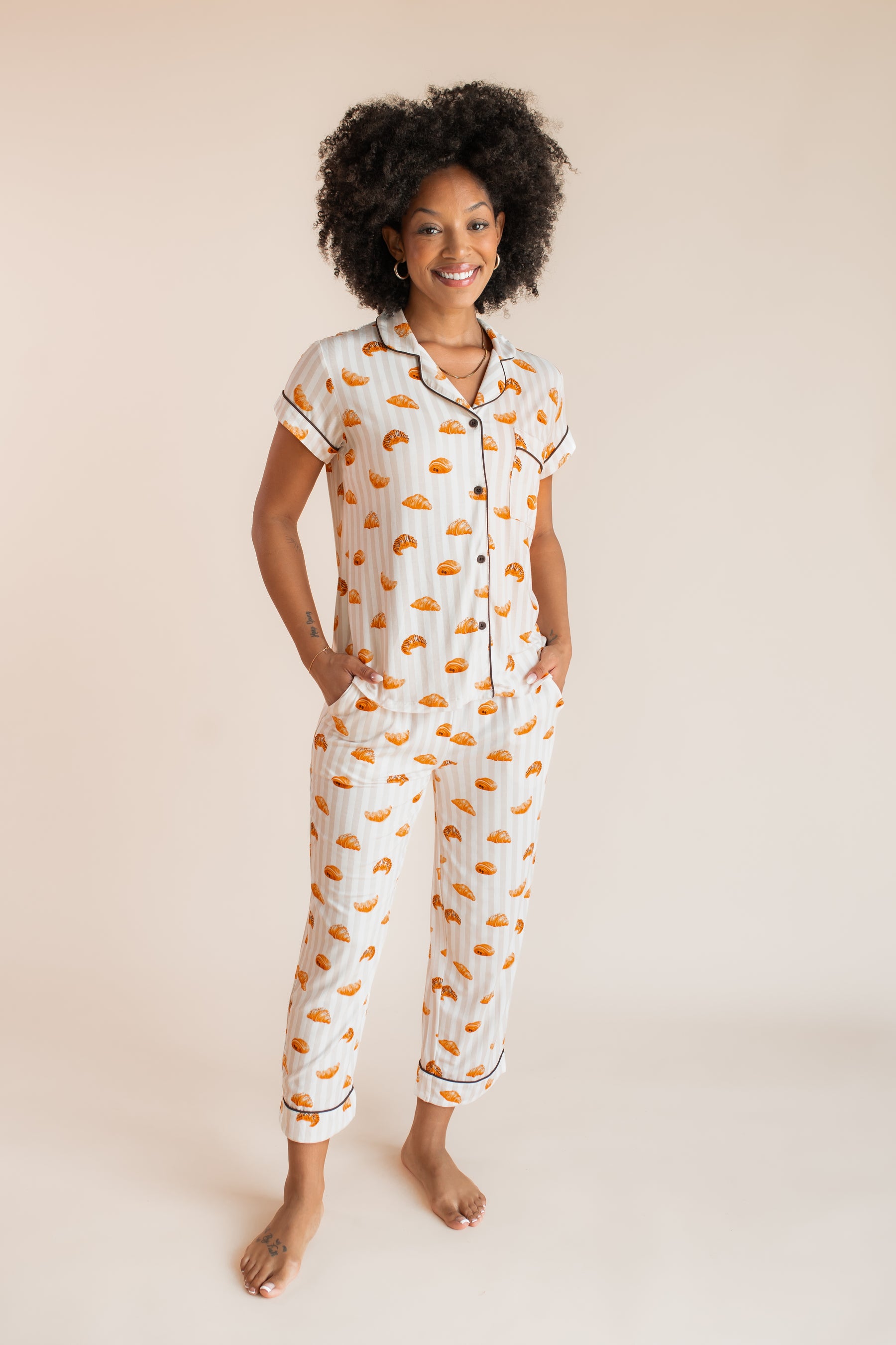 Model posing in Women's Short Sleeve Cropped Pajama Set with Croissant print on a beige background