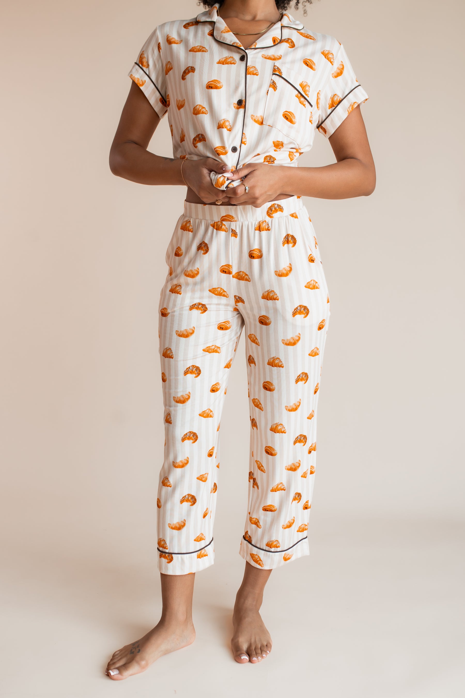 Model showcasing the top part of pajamas of Women's Short Sleeve Cropped Pajama Set with Croissant print on a beige background