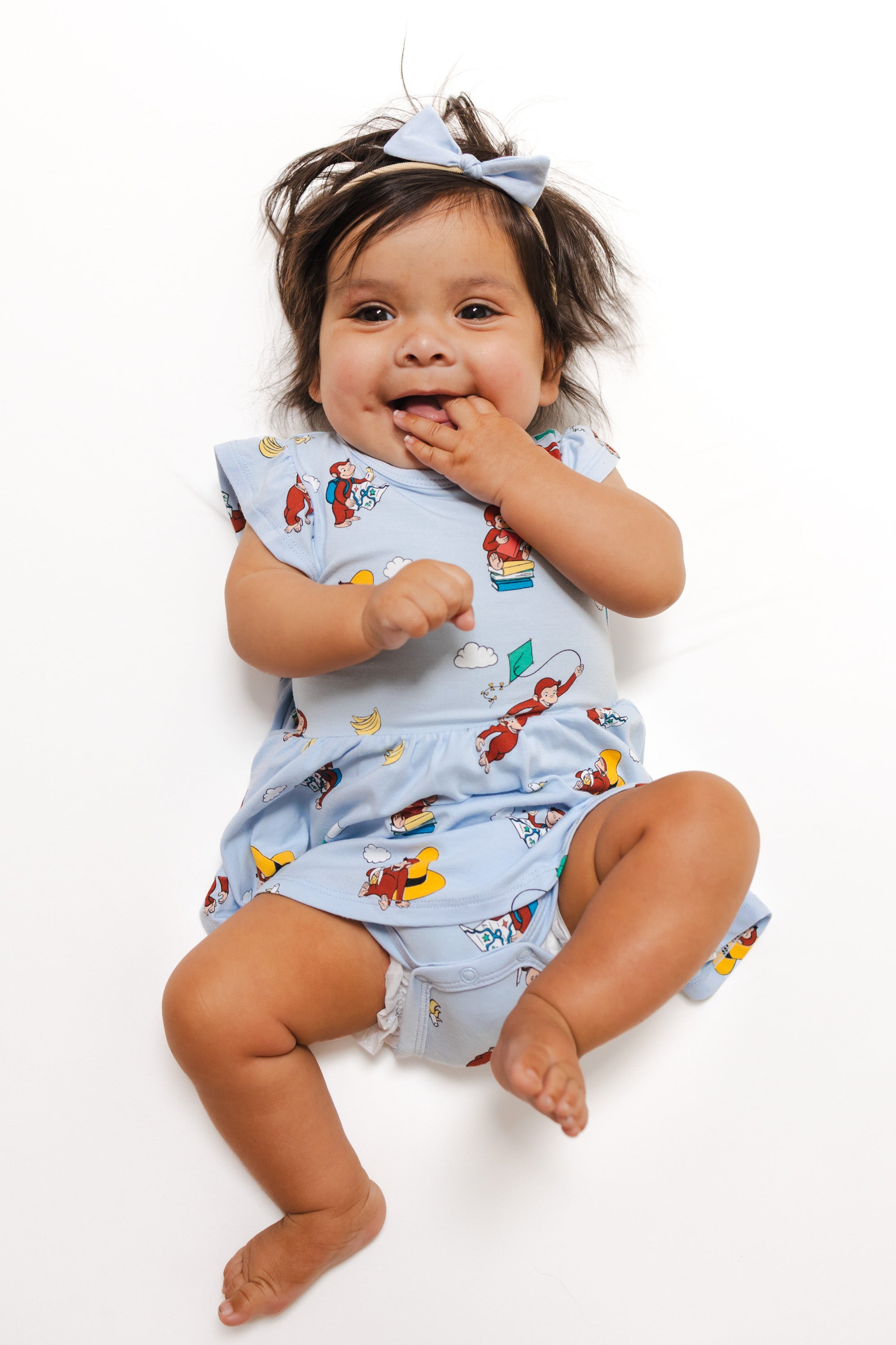 Baby wearing Twirl Bodysuit Dress in Curious George print on a white background