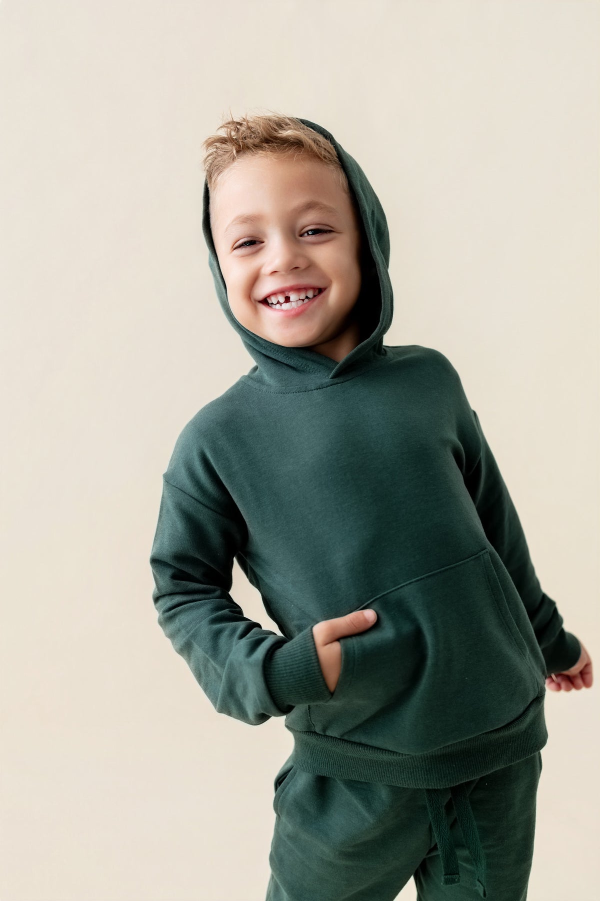 Boy wearing Hoodie in Cypress color on a beige background
