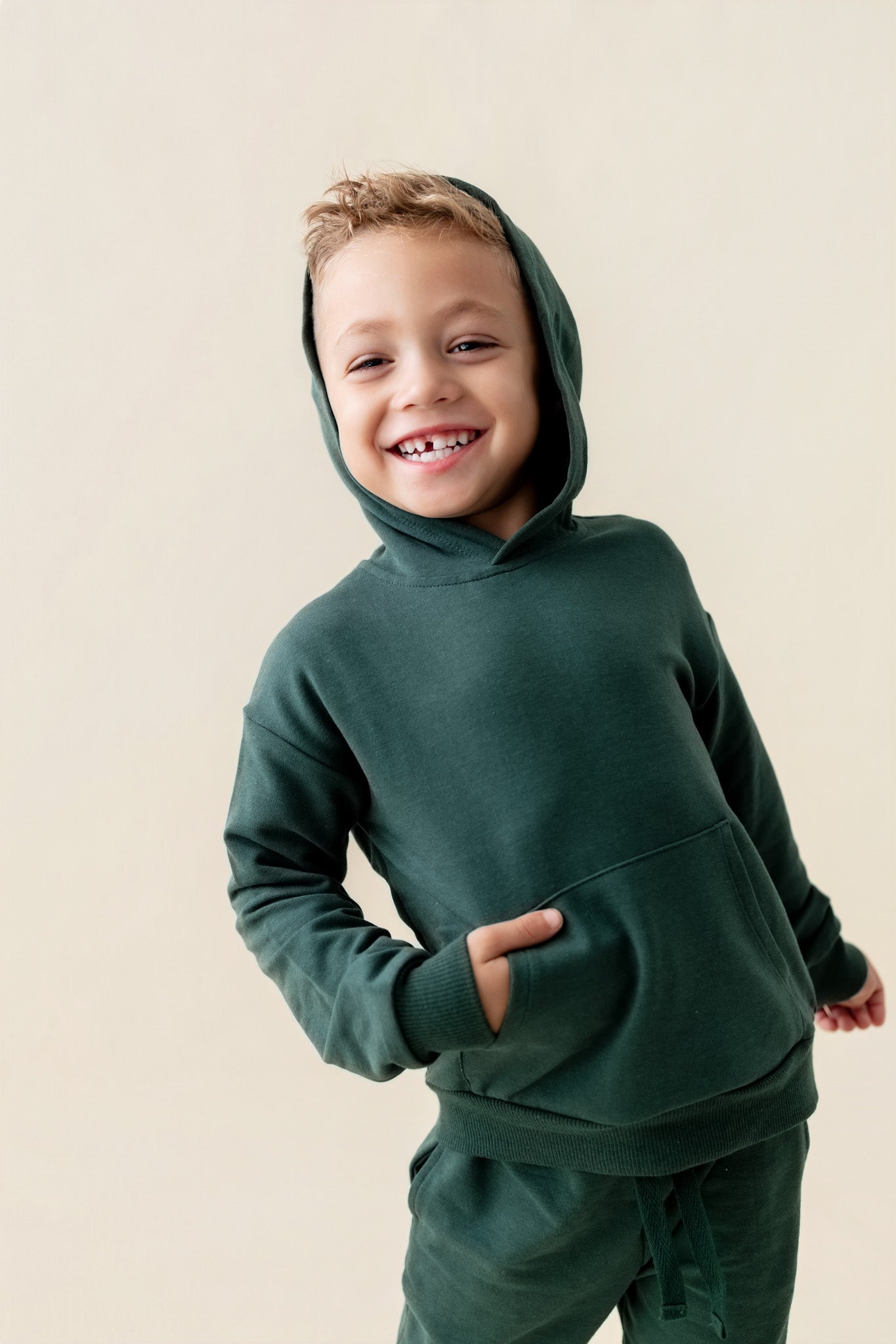 Boy wearing Hoodie in Cypress color on a beige background