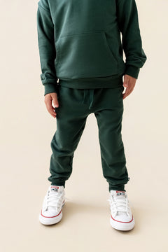 Modal wearing Jogger Pant in Cypress color under cypress color hoodie on a beige background