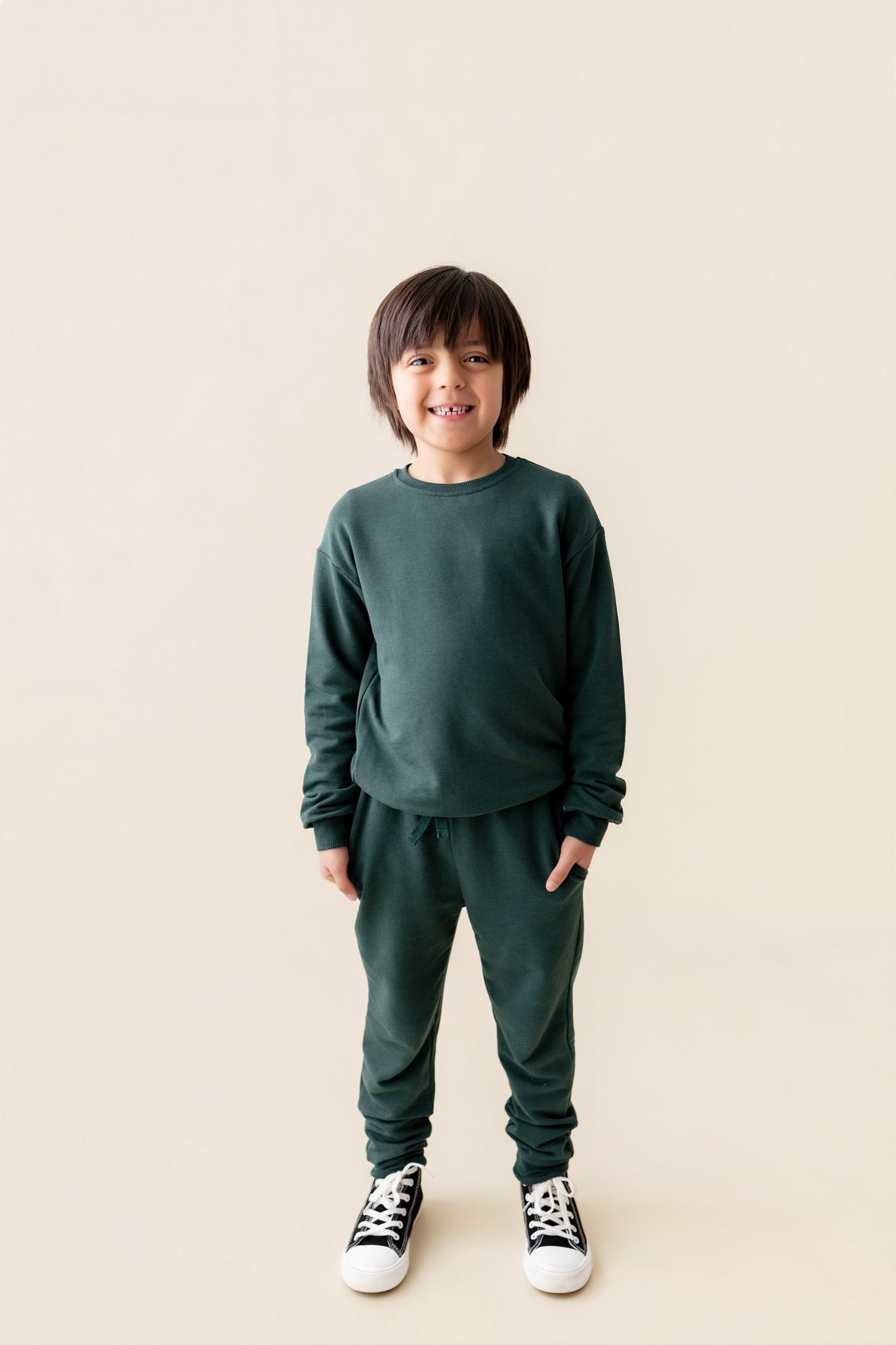 Boy wearing Jogger Pant in Cypress color under cypress color sweatshirt on a beige background