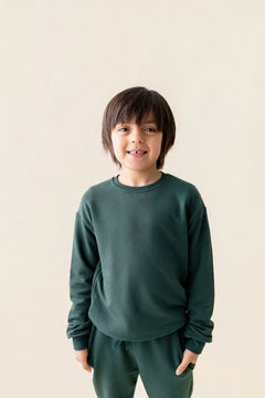 Boy wearing Sweatshirt in Cypress color over similar color jogger pant on a beige background