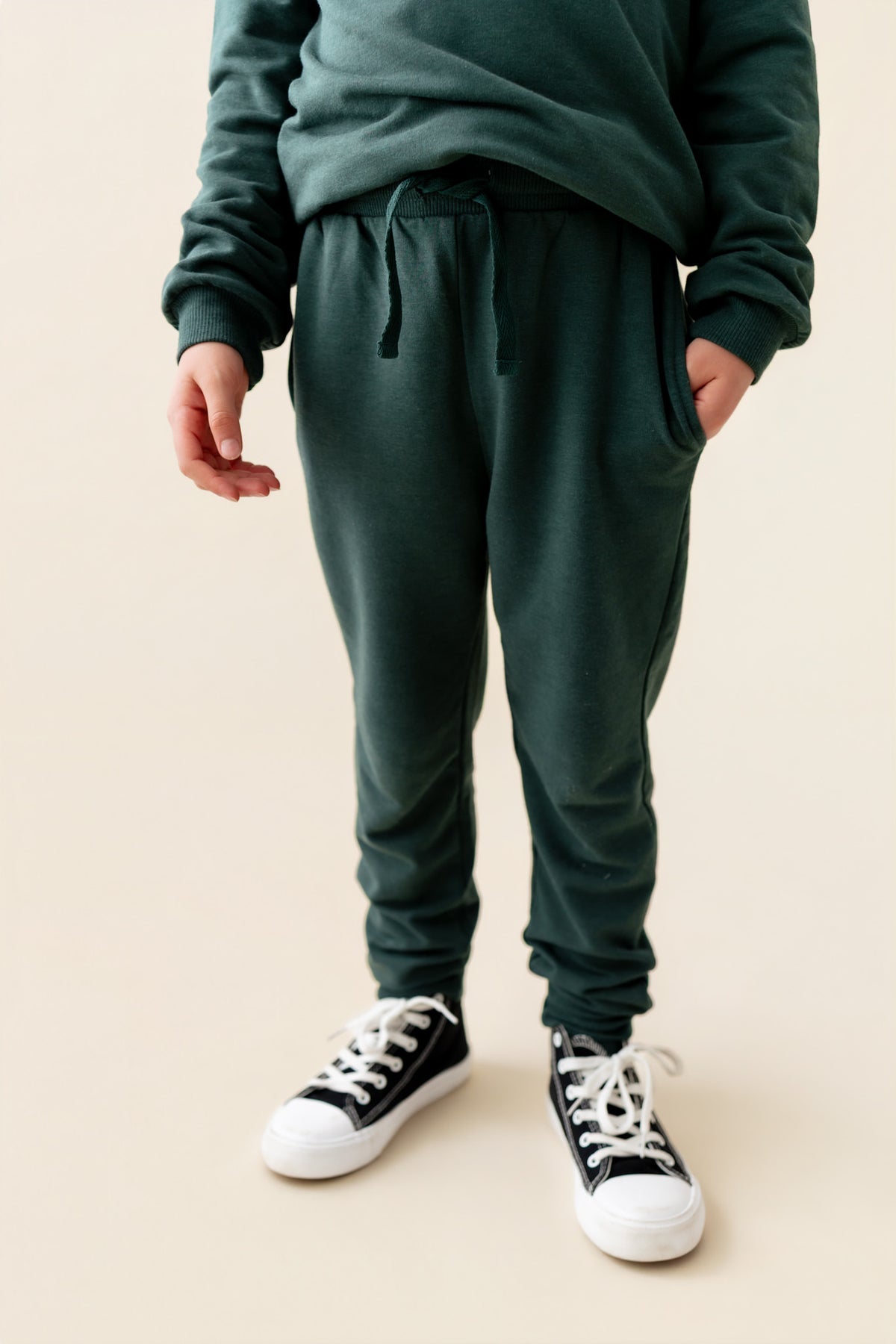 Modal wearing Jogger Pant in Cypress color under cypress color hoodie on a beige background