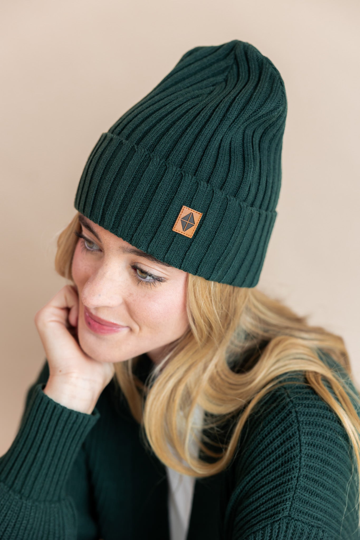 Modal wearing chunky knit adult ribbed beanie in cypress and chunky knit cardigan in cypress on a beige background