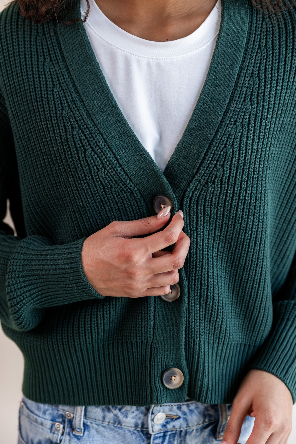 Modal showcasing front side of chunky knit cropped cardigan in cypress with buttons over blue jeans