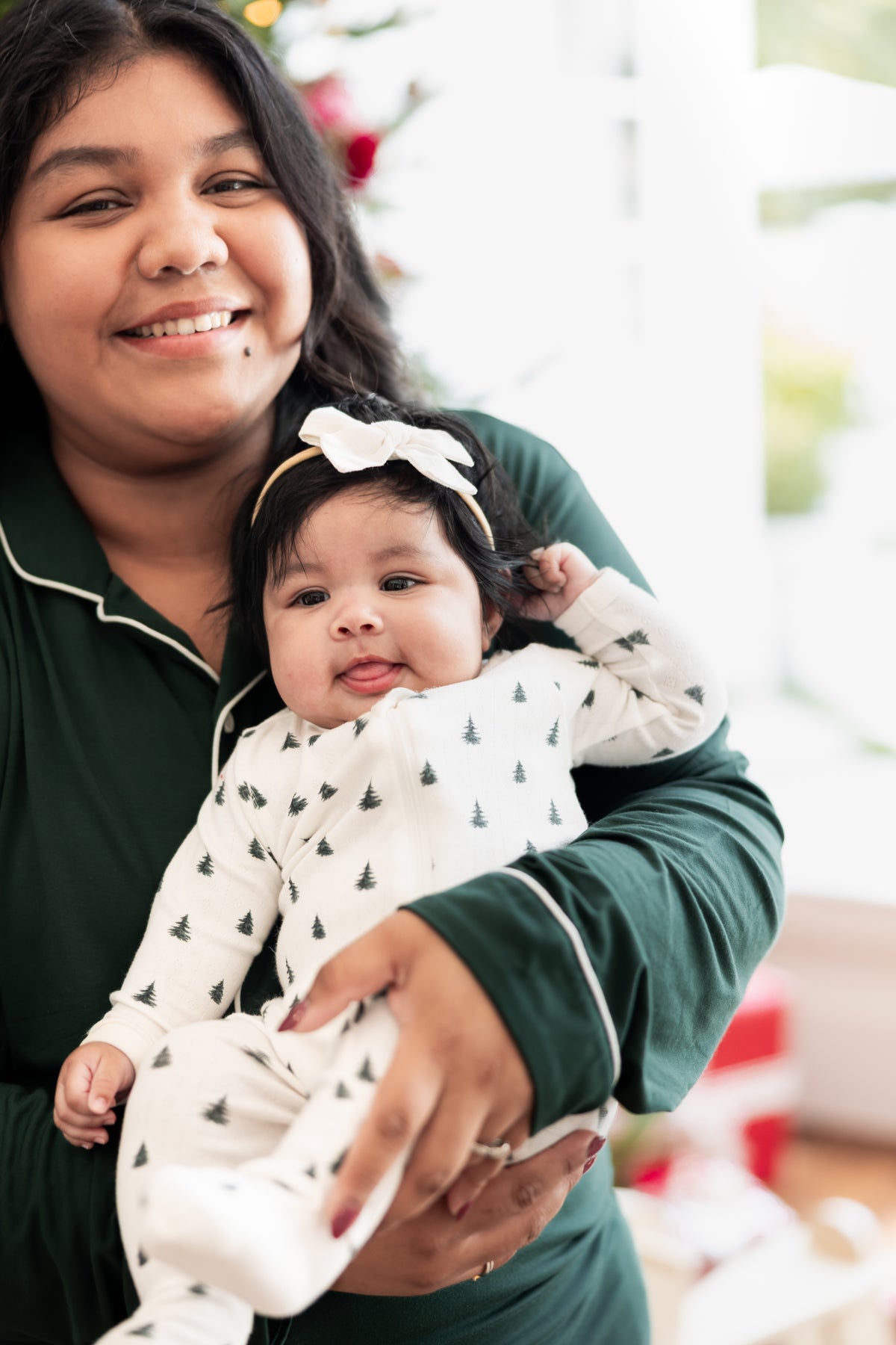 Mommy wearing long sleeve pajama set in cypress holding her Baby wearing Pointelle Zippered Footie in Christmas Trees