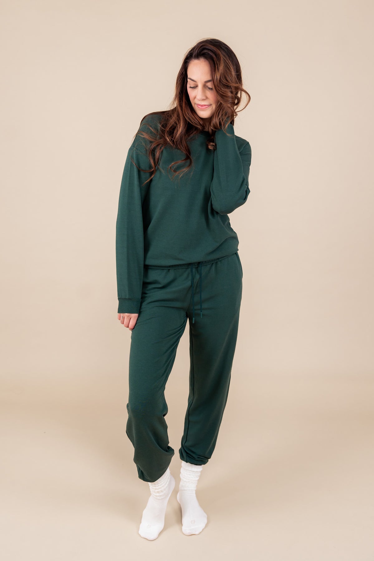 Modal posing in Women's Jogger Pant in Cypress color under similar color sweatshirt on a beige background