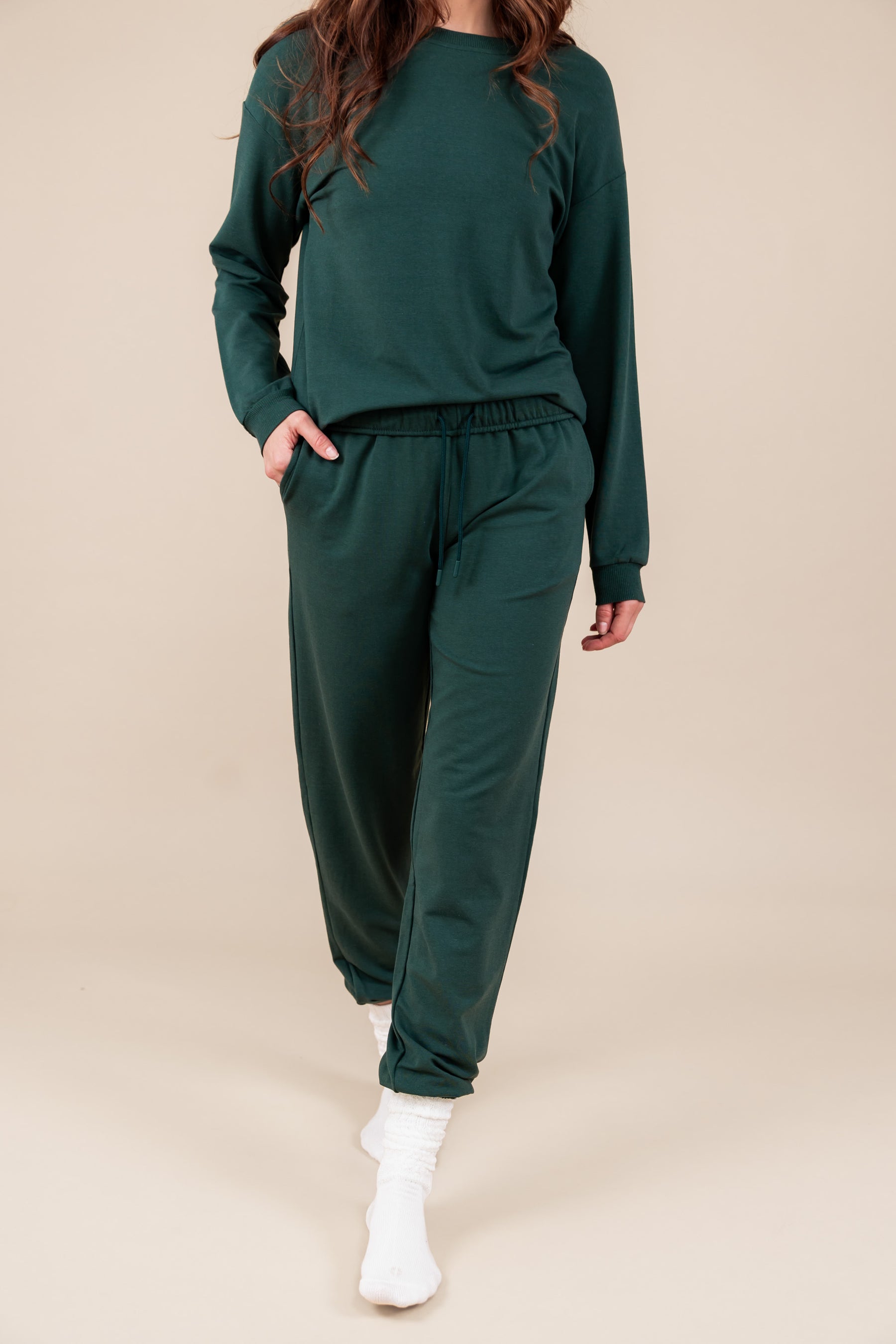 Modal wearing Women's Jogger Pant in Cypress color under similar color sweatshirt on a beige background