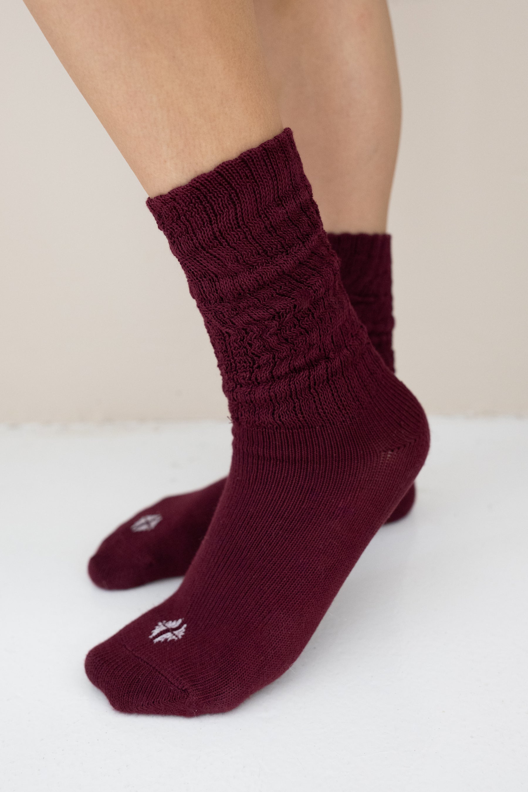 Burgundy socks worn by a person on a white surface with a beige background