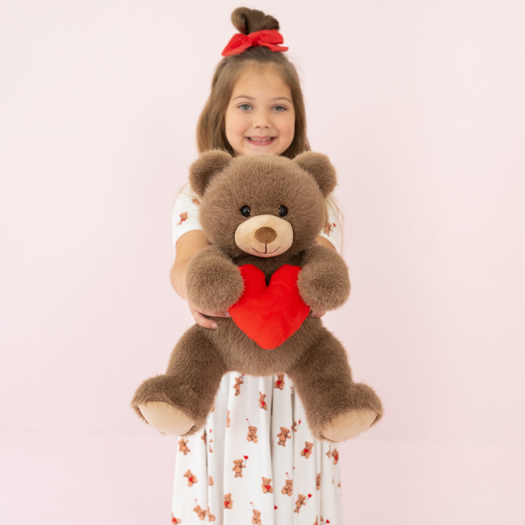 Valentine's Teddy Bear being held by a young girl wearing the Bear Hearts Twirl dress