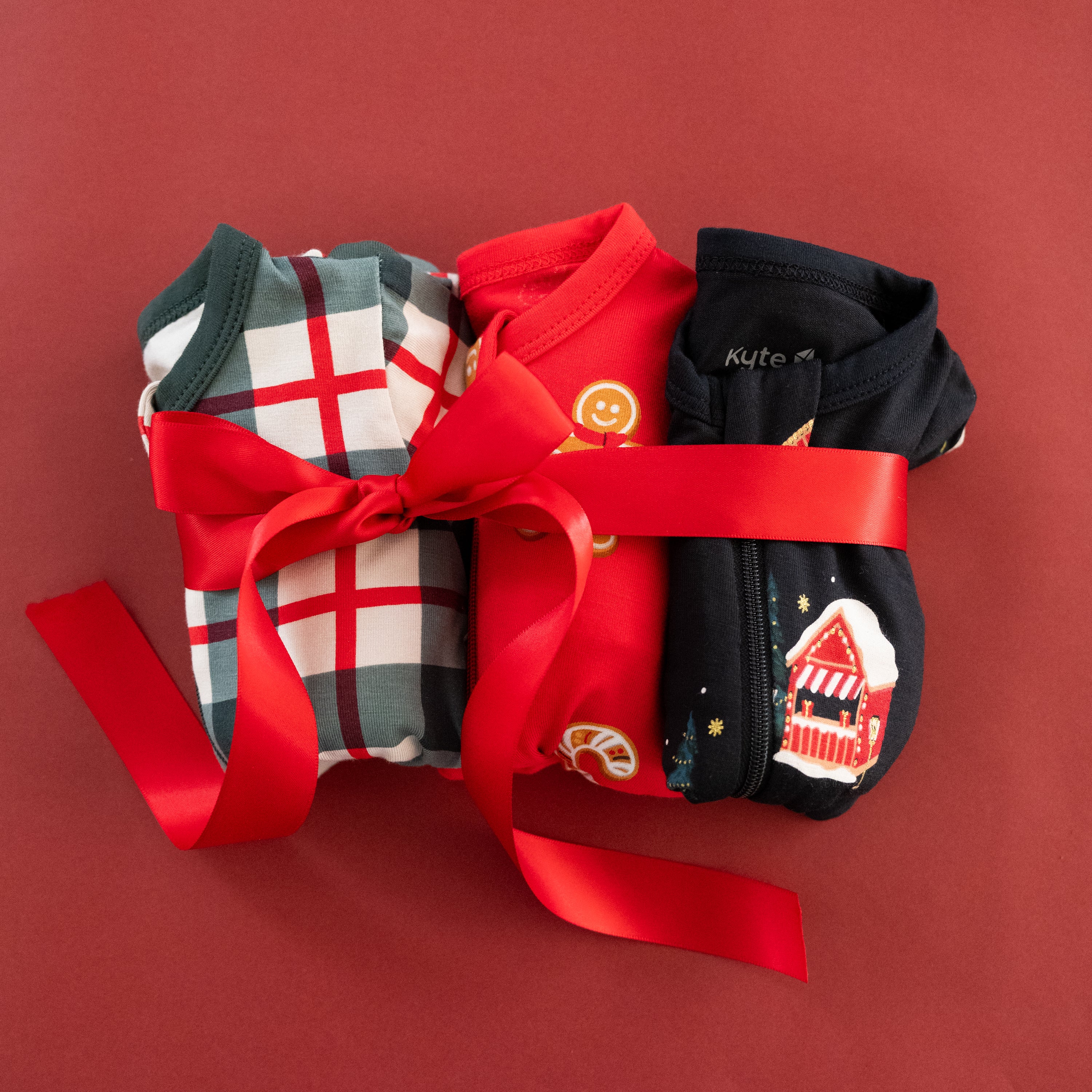 Holiday pajamas wrapped in a bright red bow on a muted red background
