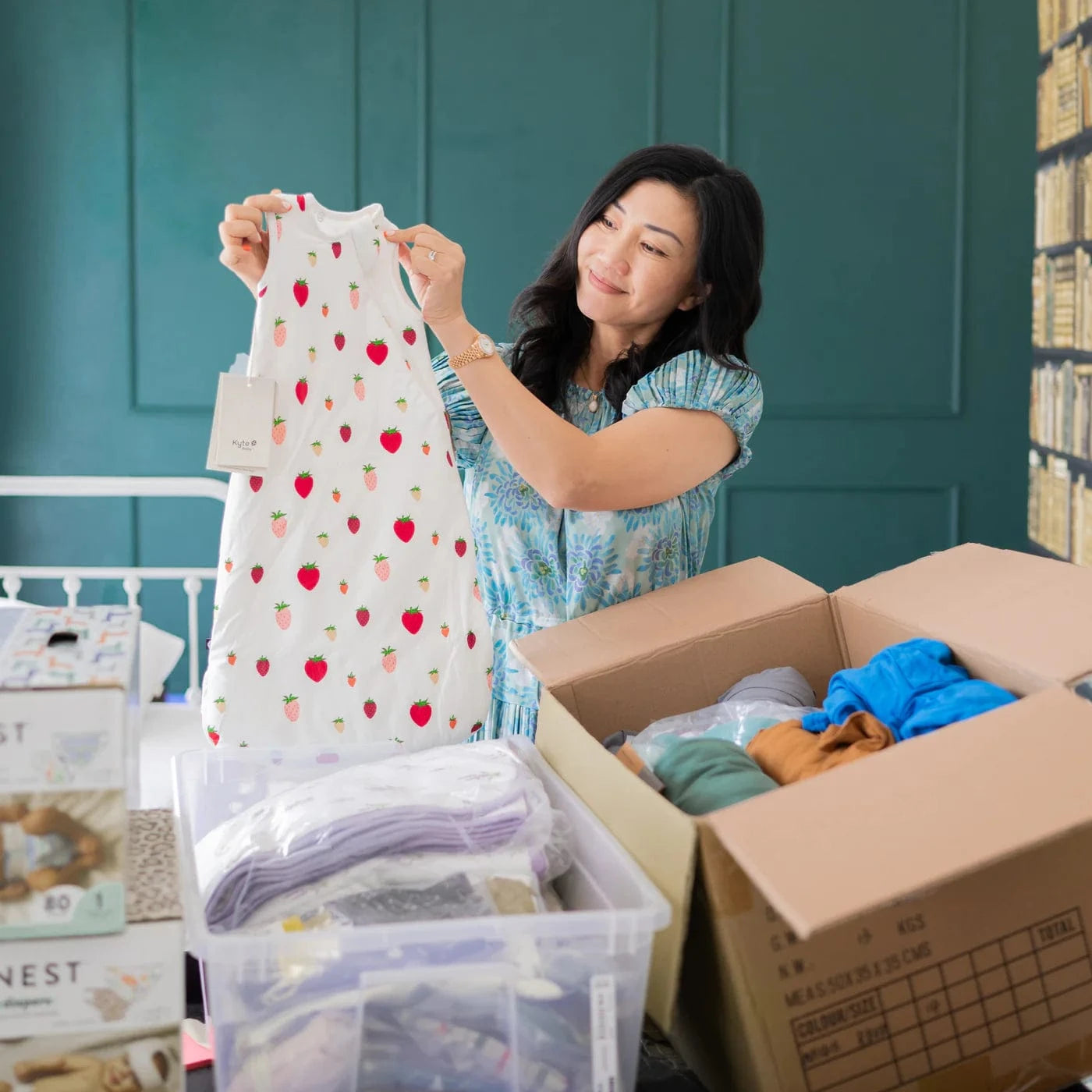 Kyte Baby owner, Ying, holding strawberry sleep bag surrounded by donation boxes