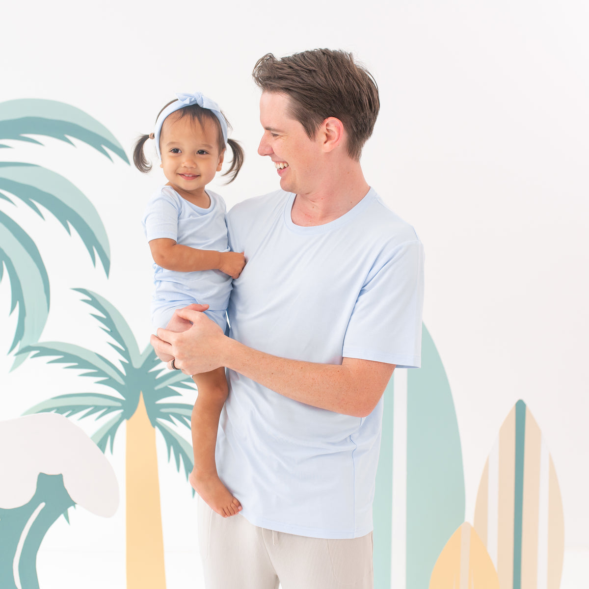 Male model wearing the Men's Crew Neck Tee in Mist while holding his daughter who is wearing the matching color in Short Sleeve Toddler Pajamas