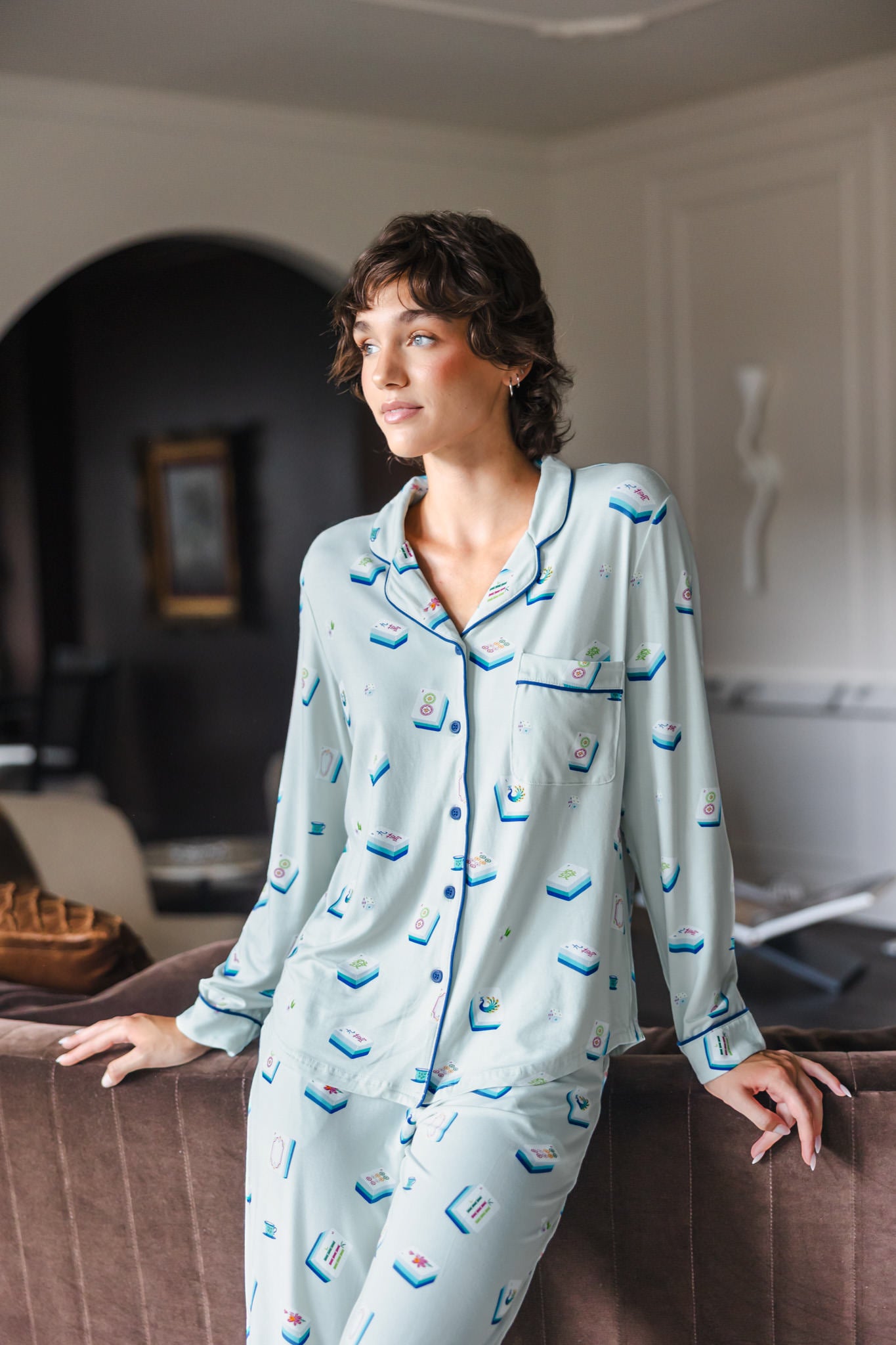 Modal posing in Long-Sleeved Women's Pajama Set in Dew Mahjong print standing against a sofa in a living room
