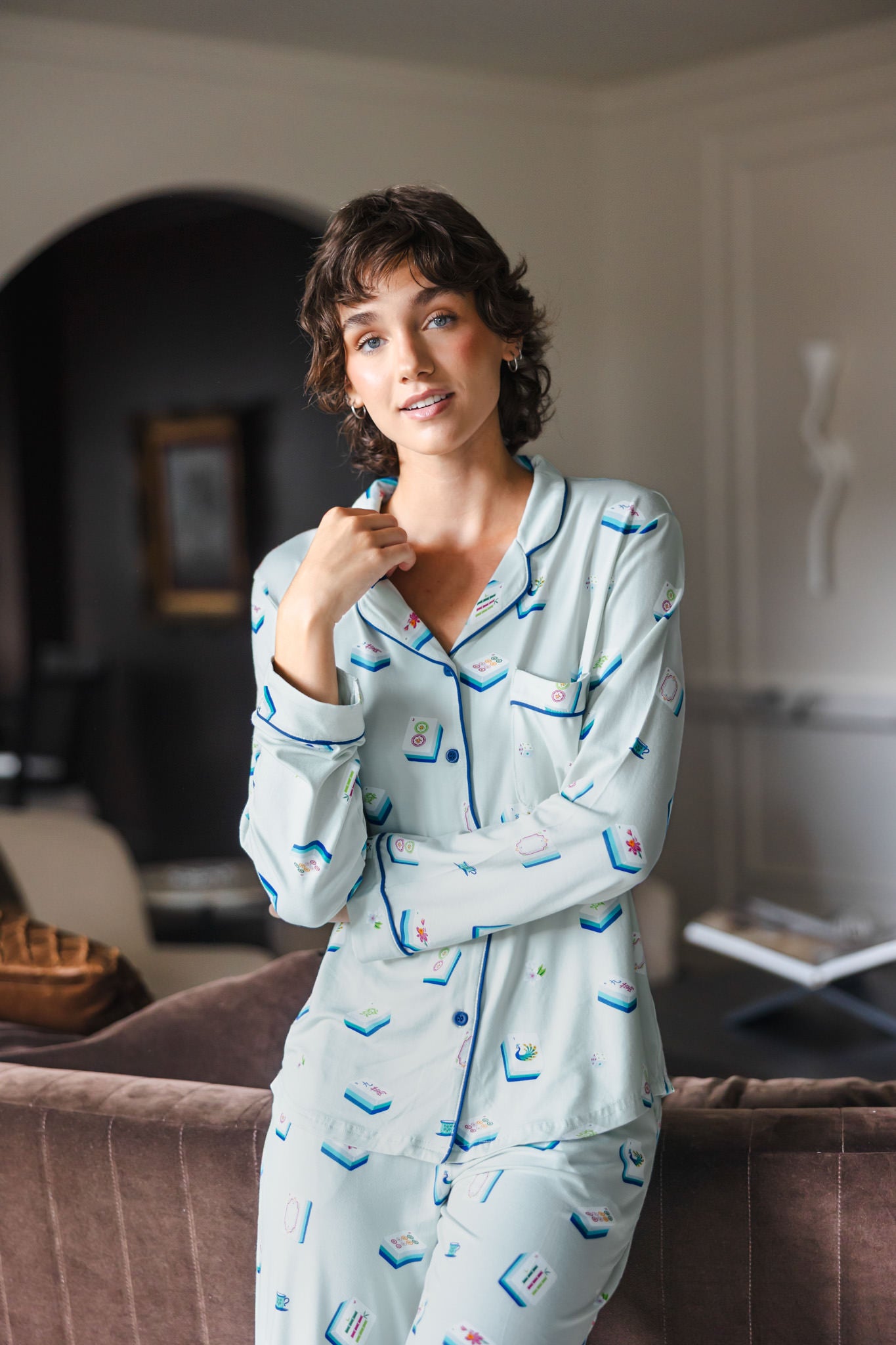 Modal wearing Long-Sleeved Women's Pajama Set in Dew Mahjong print standing against a sofa in a living room