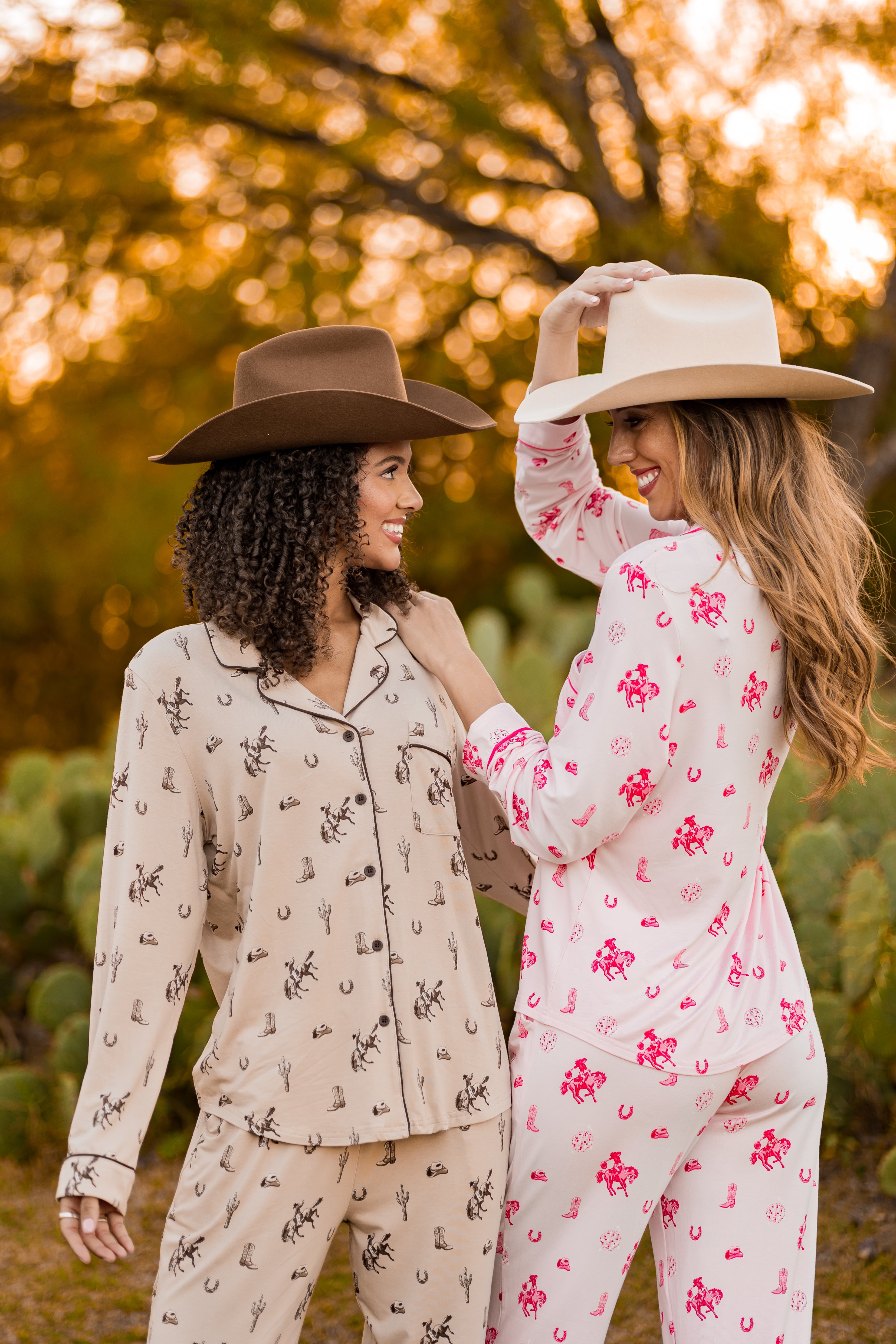 Two women wearing western patterned pajamas outdoors with a blurred natural background
