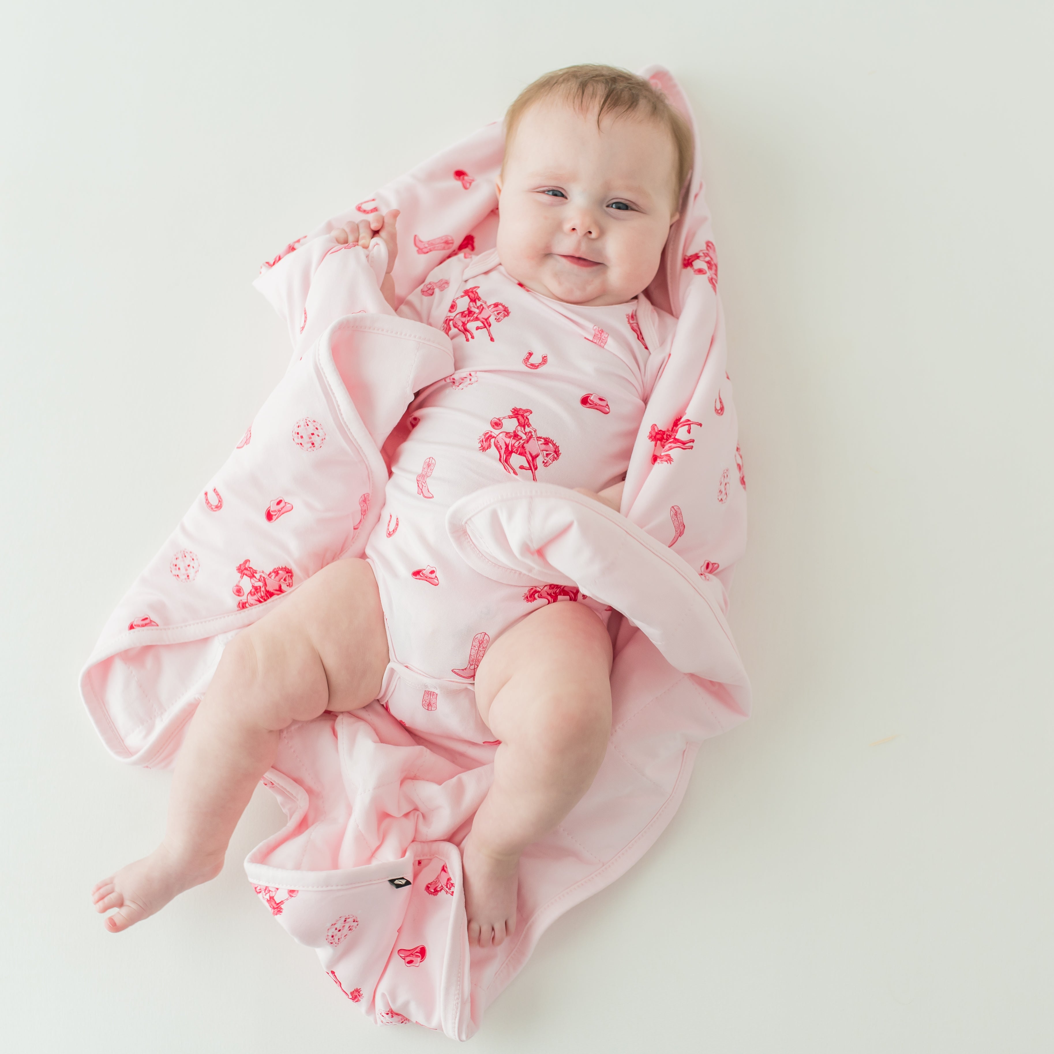 Infant laying on a Baby Blanket in Disco Cowgirl wearing a matching short sleeve bodysuit