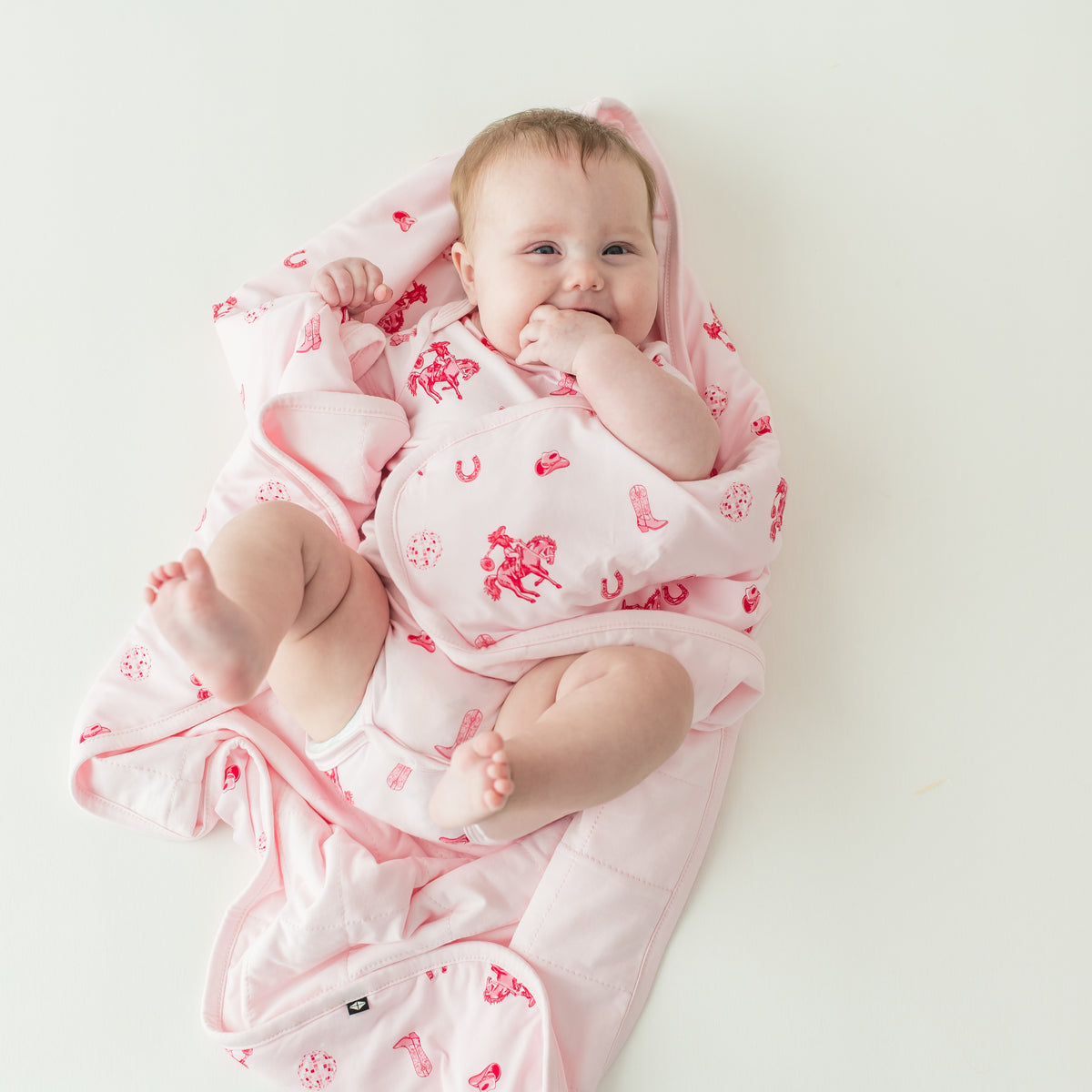 Infant girl laying wrapped in a Baby Blanket in Disco Cowgirl wearing a matching short sleeve bodysuit