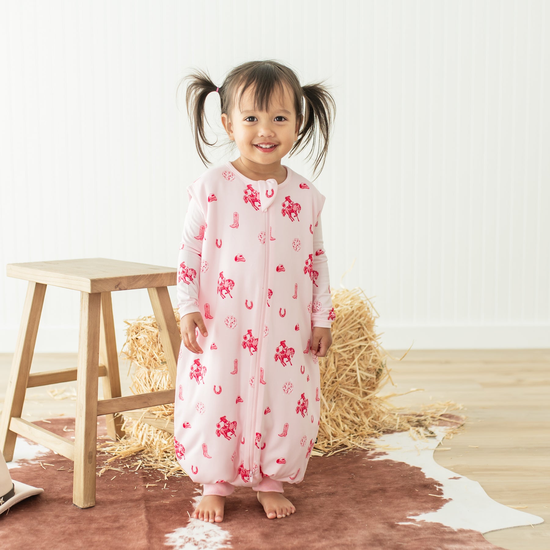Young girl standing wearing the Sleep Bag Walker in Disco Cowgirl 1.0 with the matching long sleeve toddler pajamas on underneath