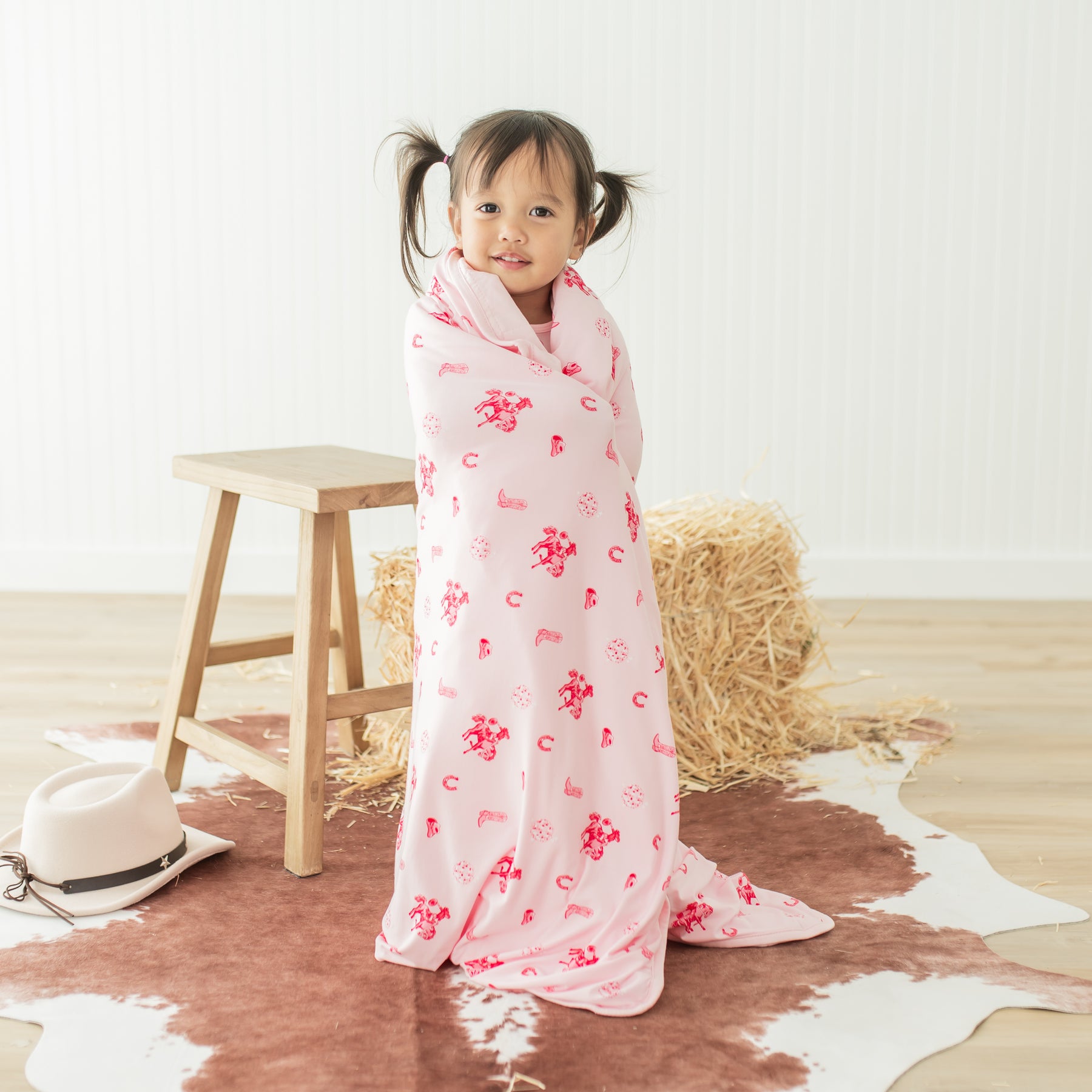 Young toddler standing with the Toddler Blanket in Disco Cowgirl 1.0 wrapped around her