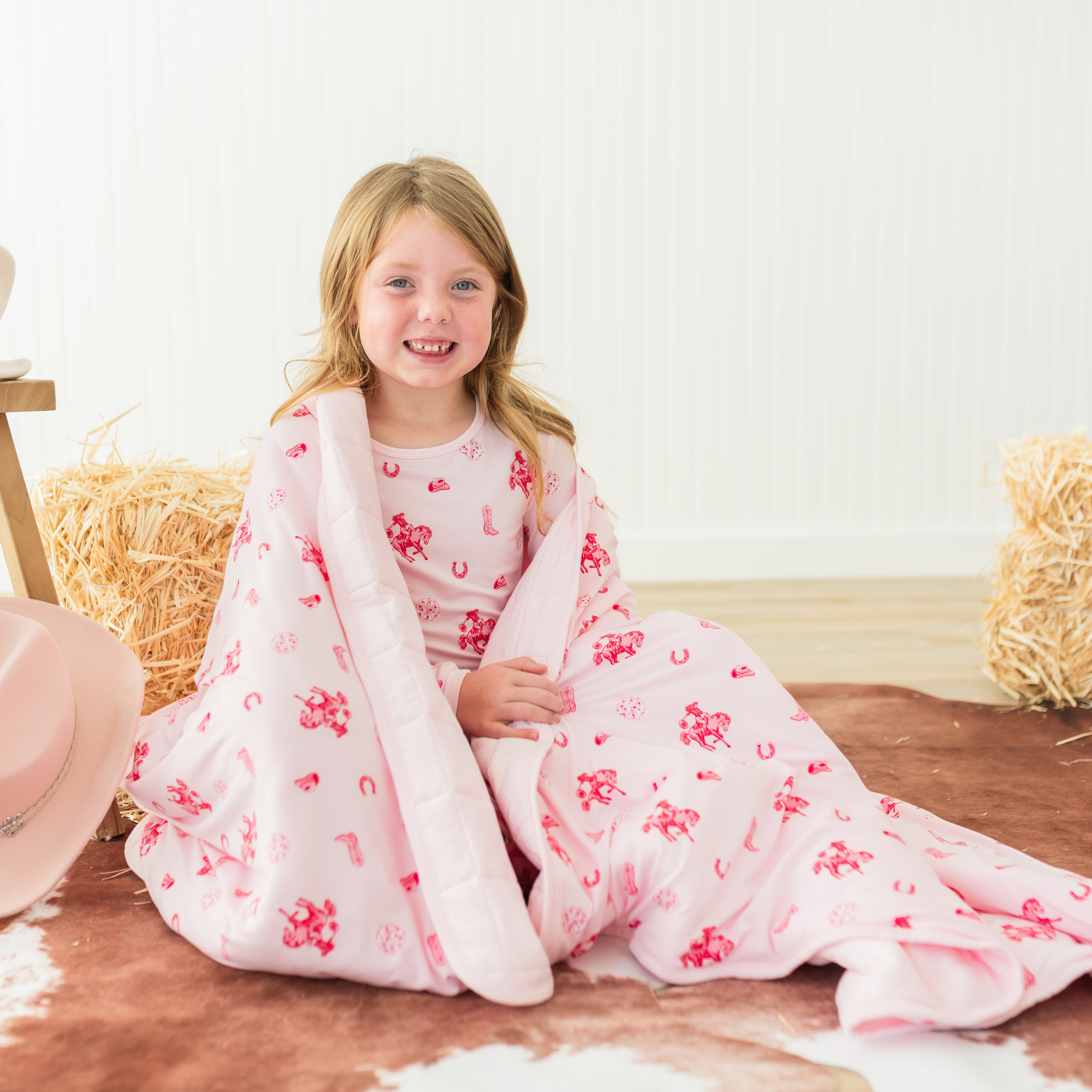 Young girl sitting on the floor with the Youth Blanket in Disco Cowgirl 2.5 wrapped around her