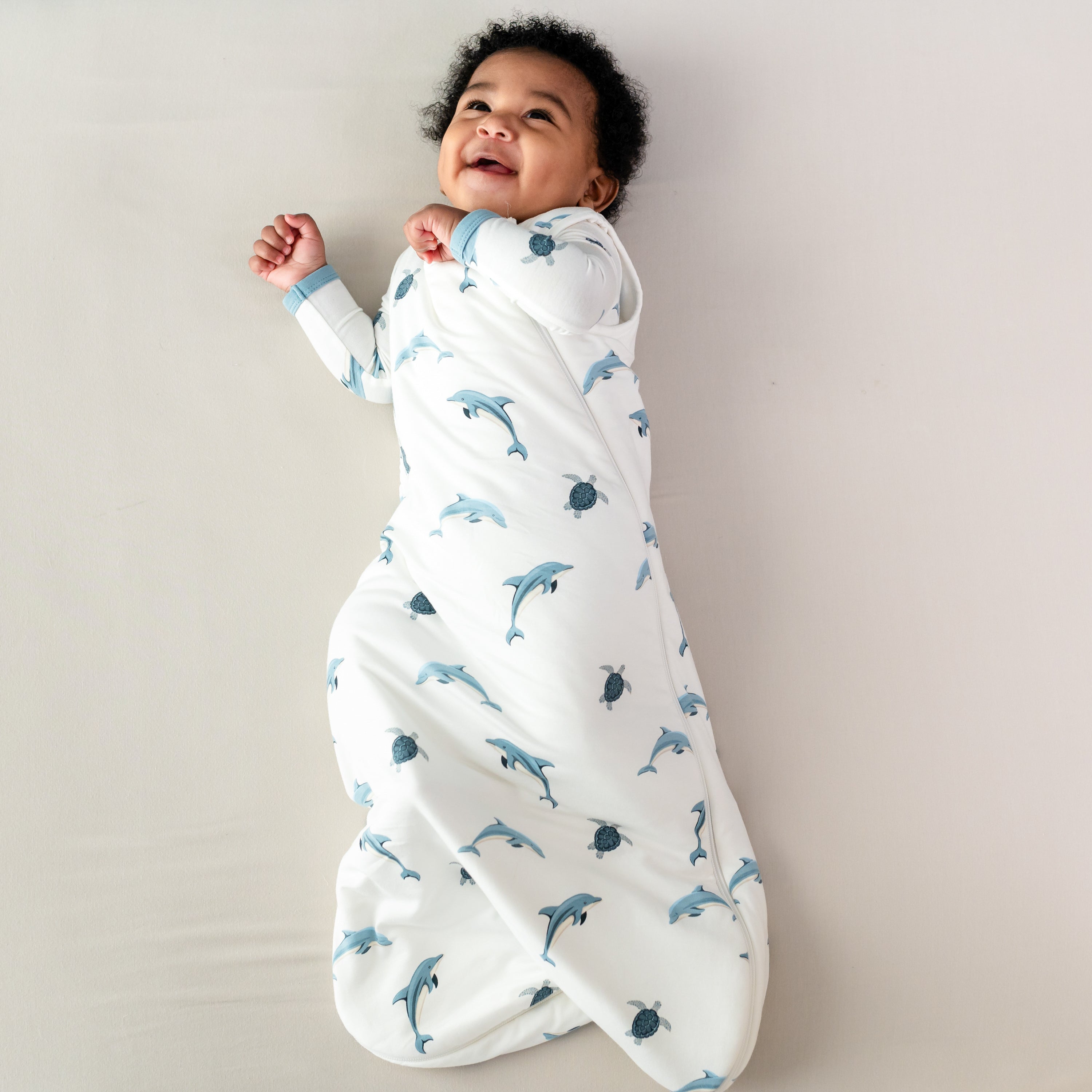 Baby wearing Kyte Baby Sleep Bag in Dolphin 1.0