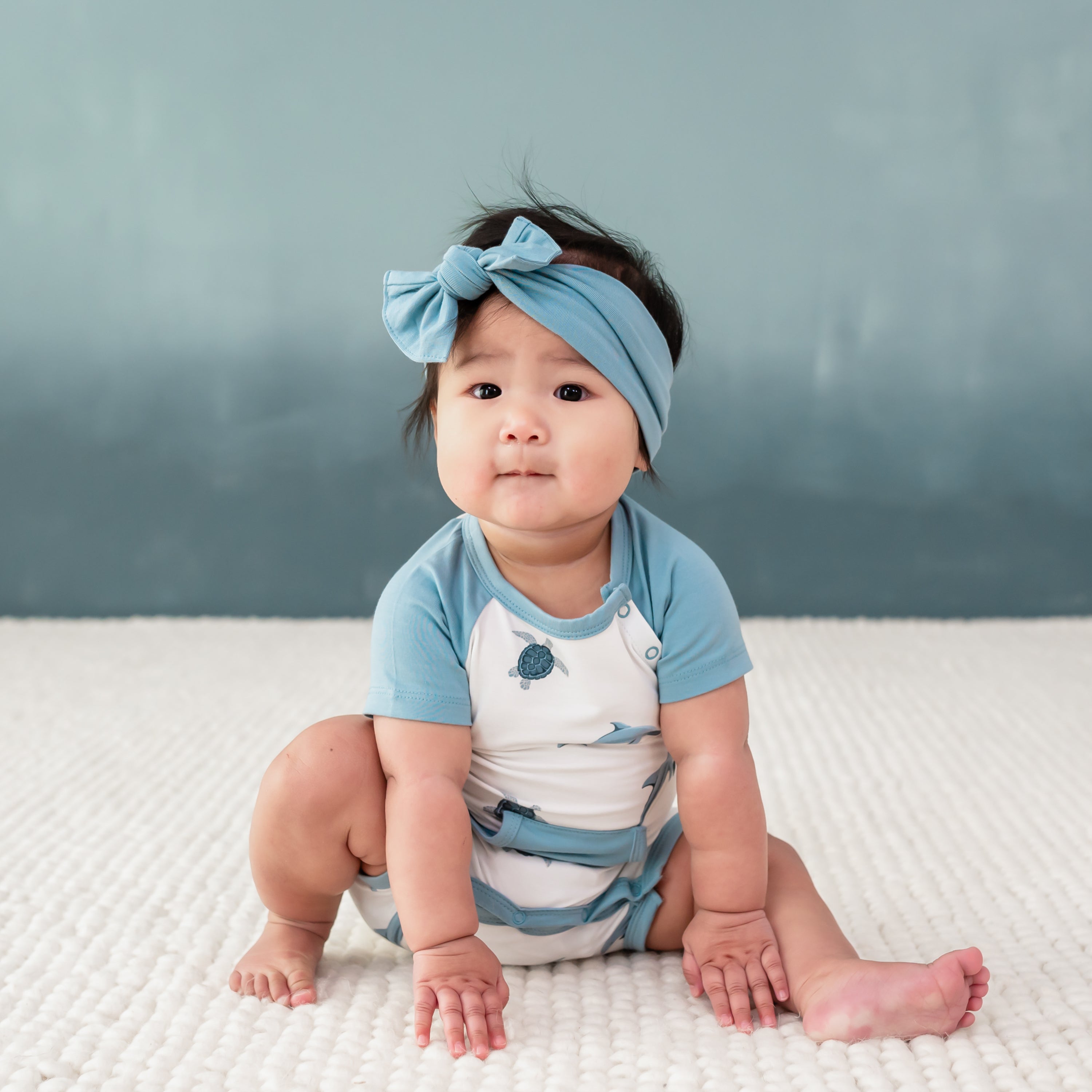 Baby wearing Shortall in Dolphin and dusty blue bow