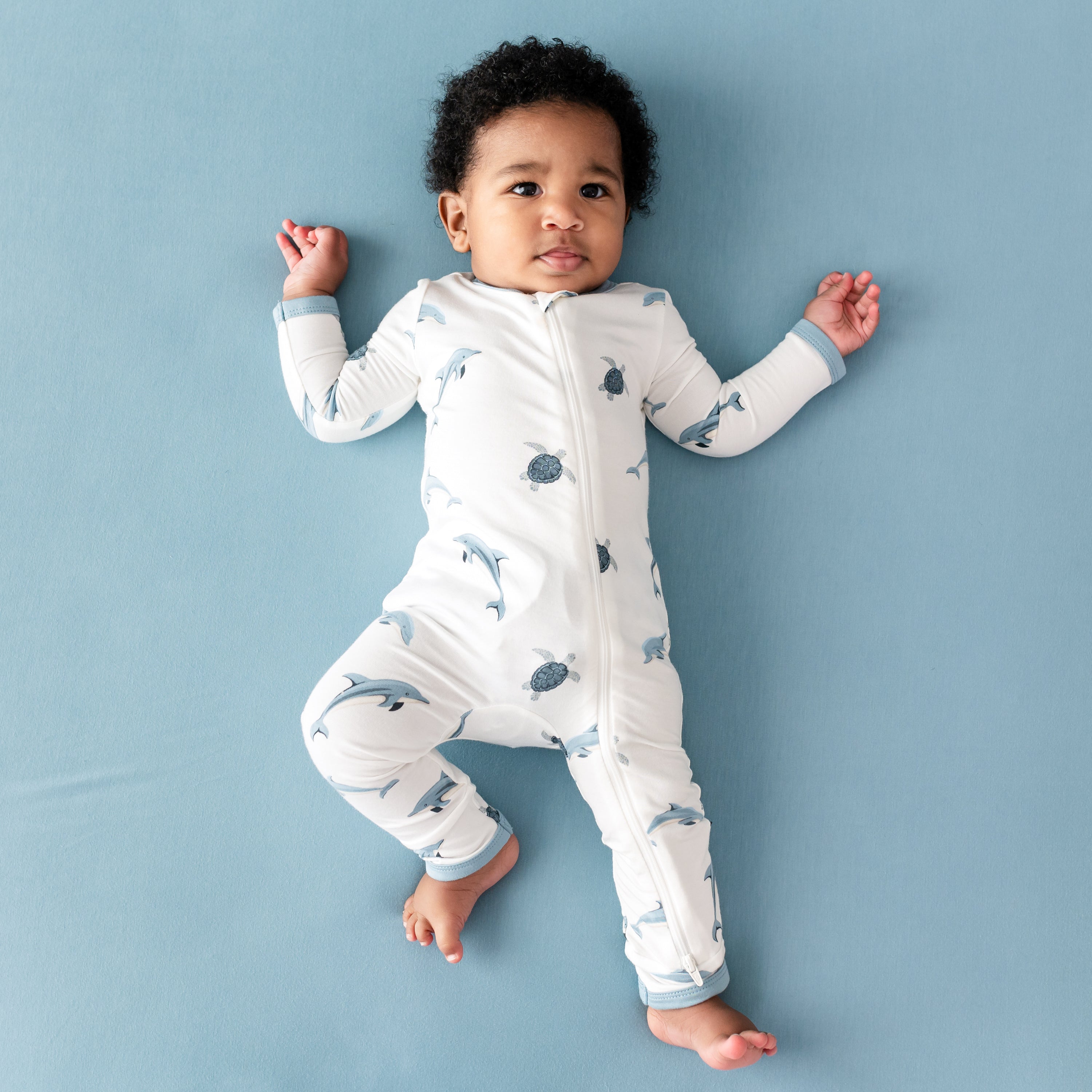 Baby wearing Kyte Zippered Romper in Dolphin