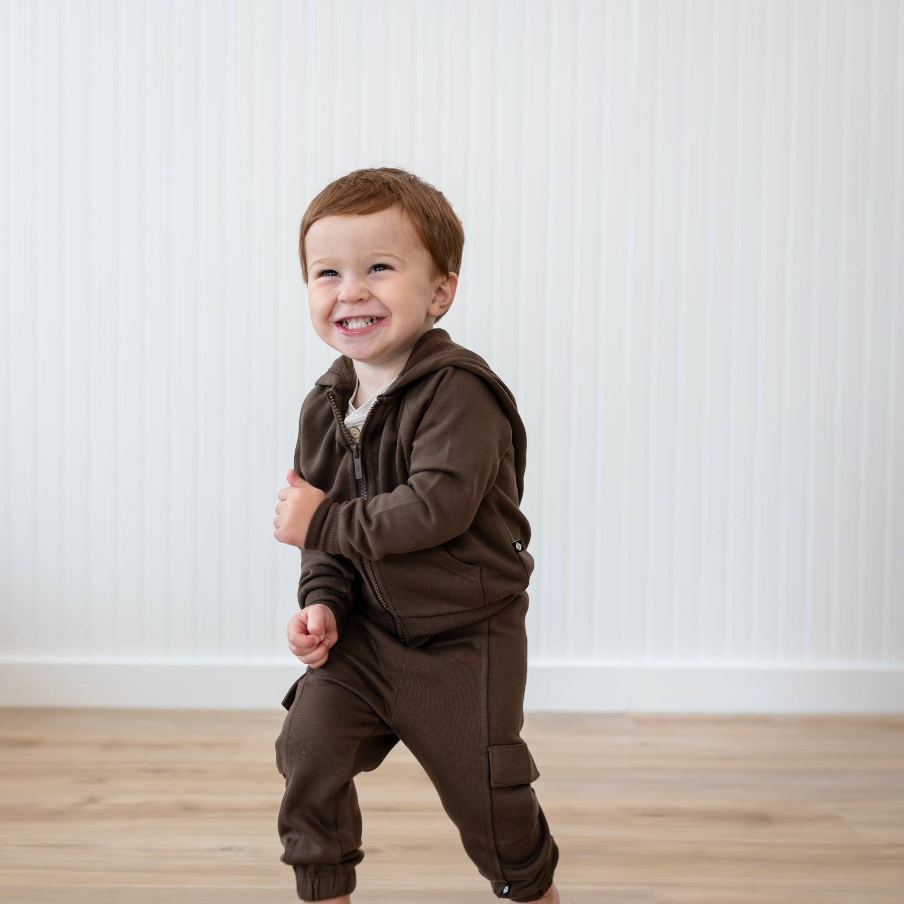 Smiling young boy walking wearing the Fleece Zip Up Hoodie in Espresso and matching fleece cargo pant