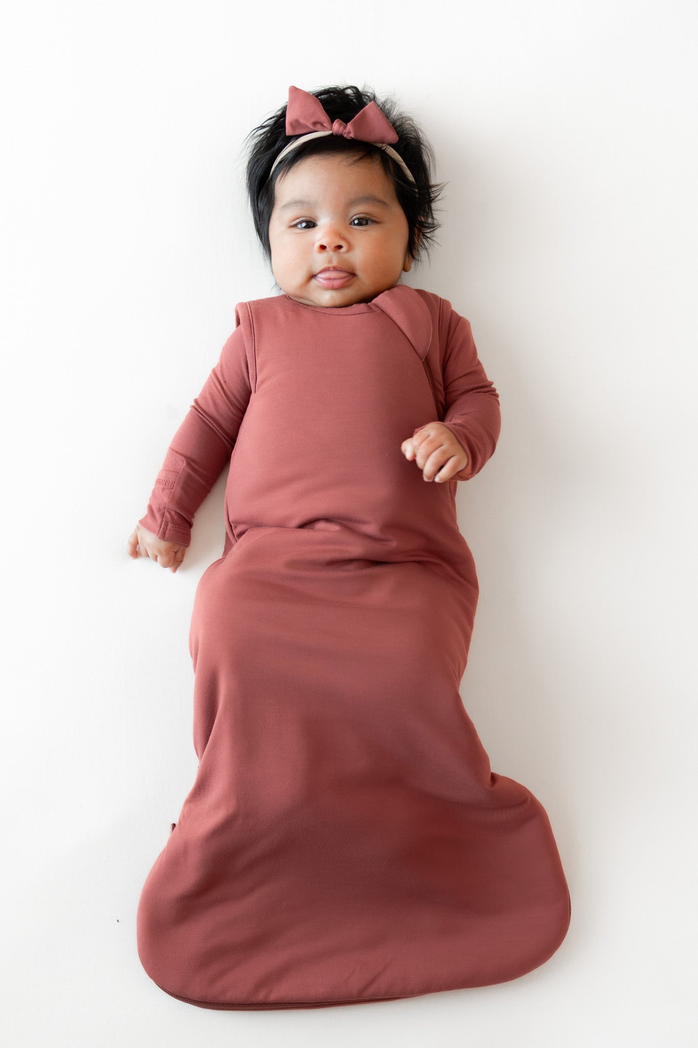 Baby wearing Tiny Nylon Bow in Ember with sleep bag in ember on a white background