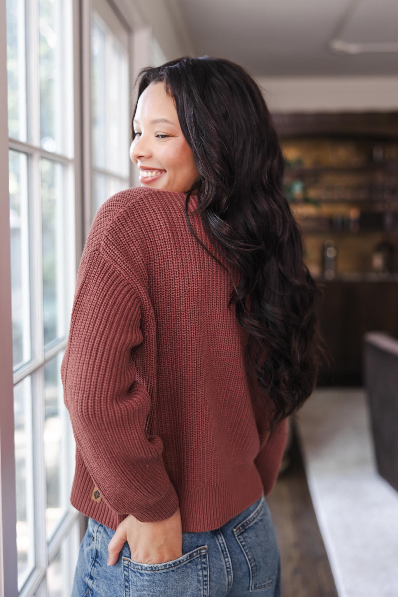 Modal showcasing the back side of Chunky Knit Women's Cropped Cardigan In Ember over blue jeans