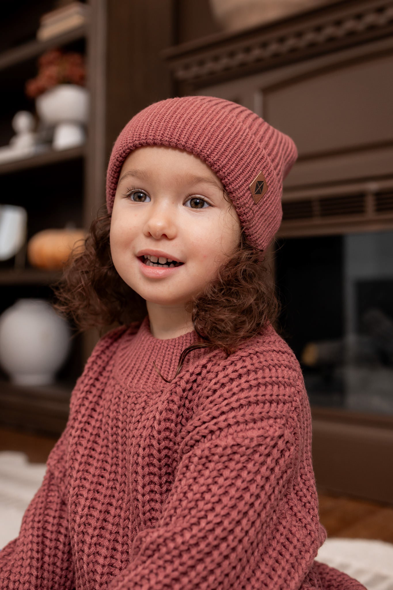 Girl wearing Chunky Knit Pom Beanie in Ember over Chunky knit sweater in ember