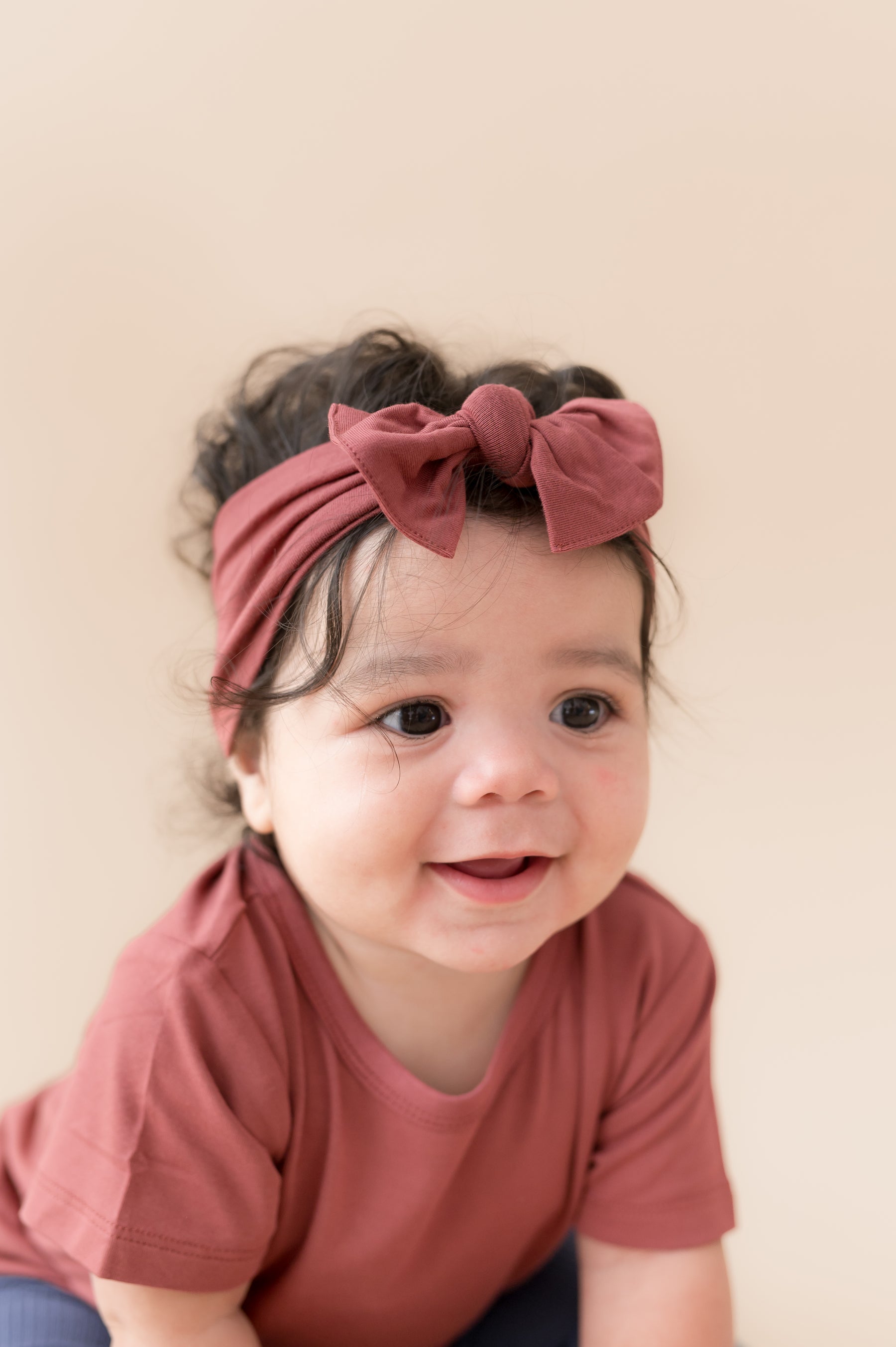 Child wearing Toddler Basic Tee in Ember with similar color knotted bow headband