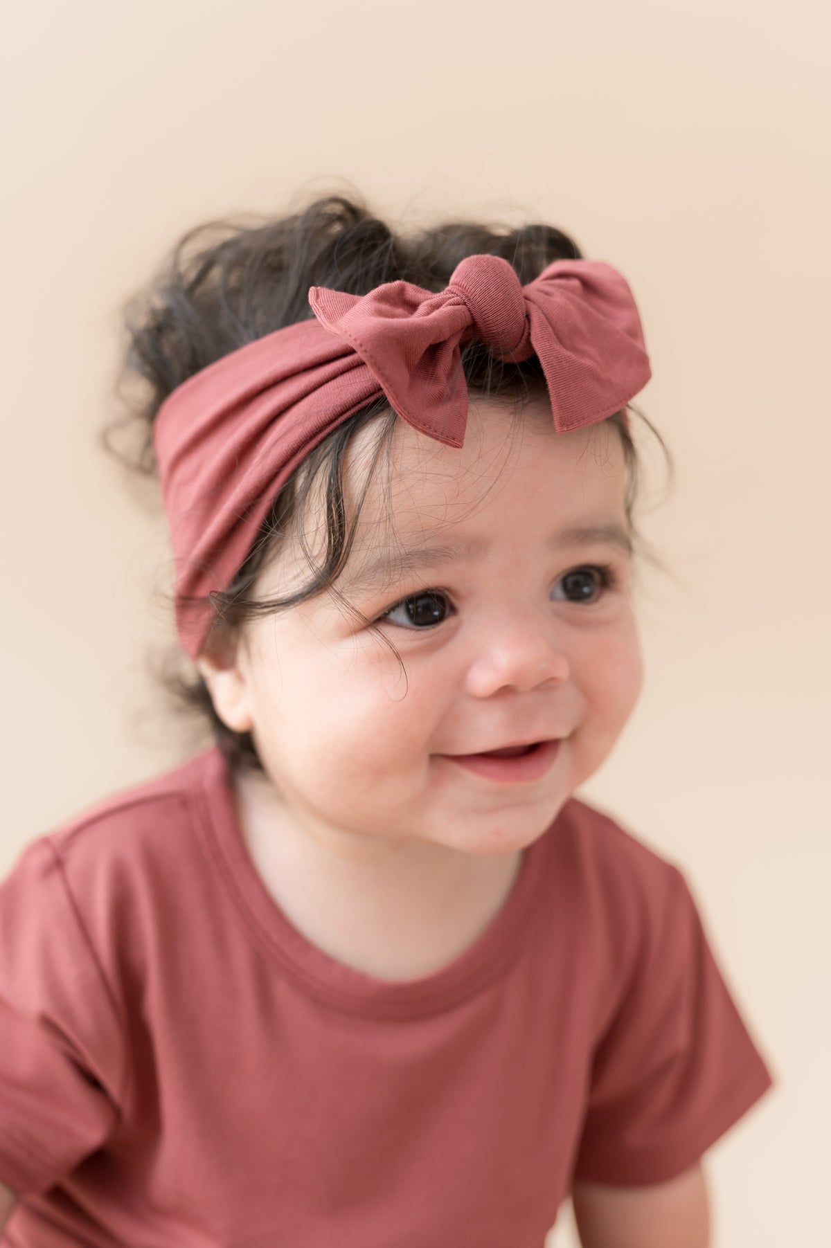 Child wearing Toddler Basic Tee in Ember with similar color knotted bow headband