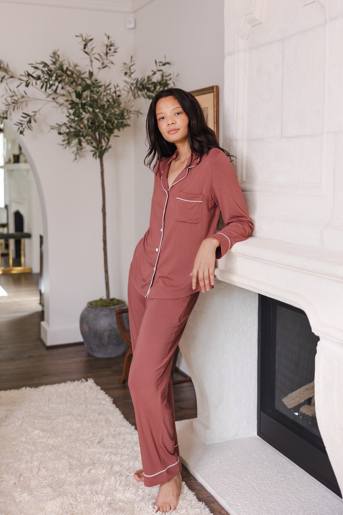 Modal wearing Long-Sleeved Women's Pajama Set in Ember standing against a wall