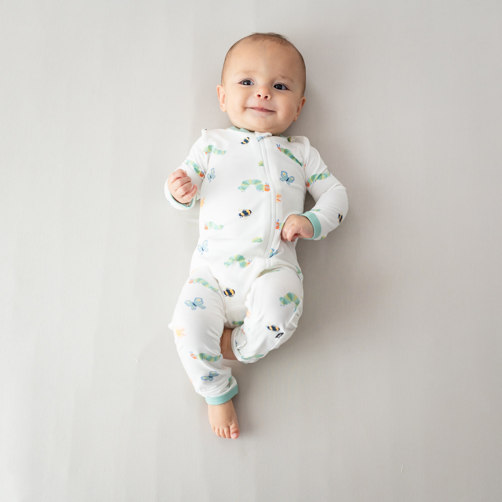 Baby laying wearing Kyte Baby Romper in The Very Hungry Caterpillar and Friends print