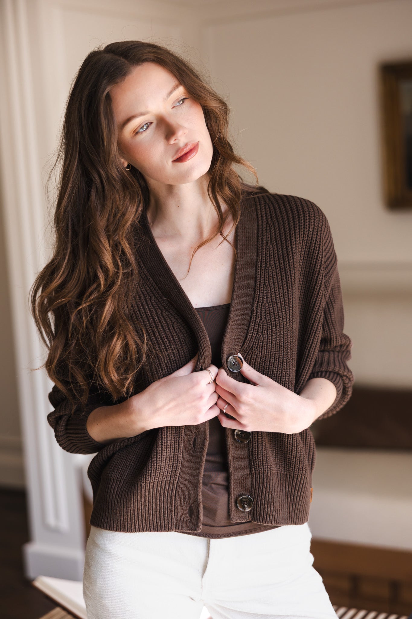Modal holding the front of Chunky Knit Women's Cropped Cardigan in Espresso over white pants