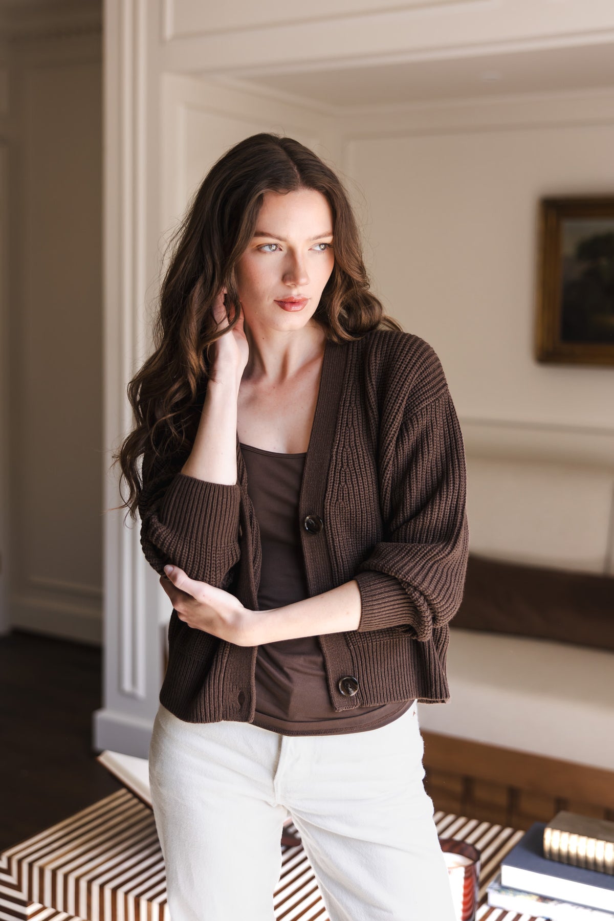 Modal posing in Chunky Knit Women's Cropped Cardigan in Espresso over similar color camisole and white pants