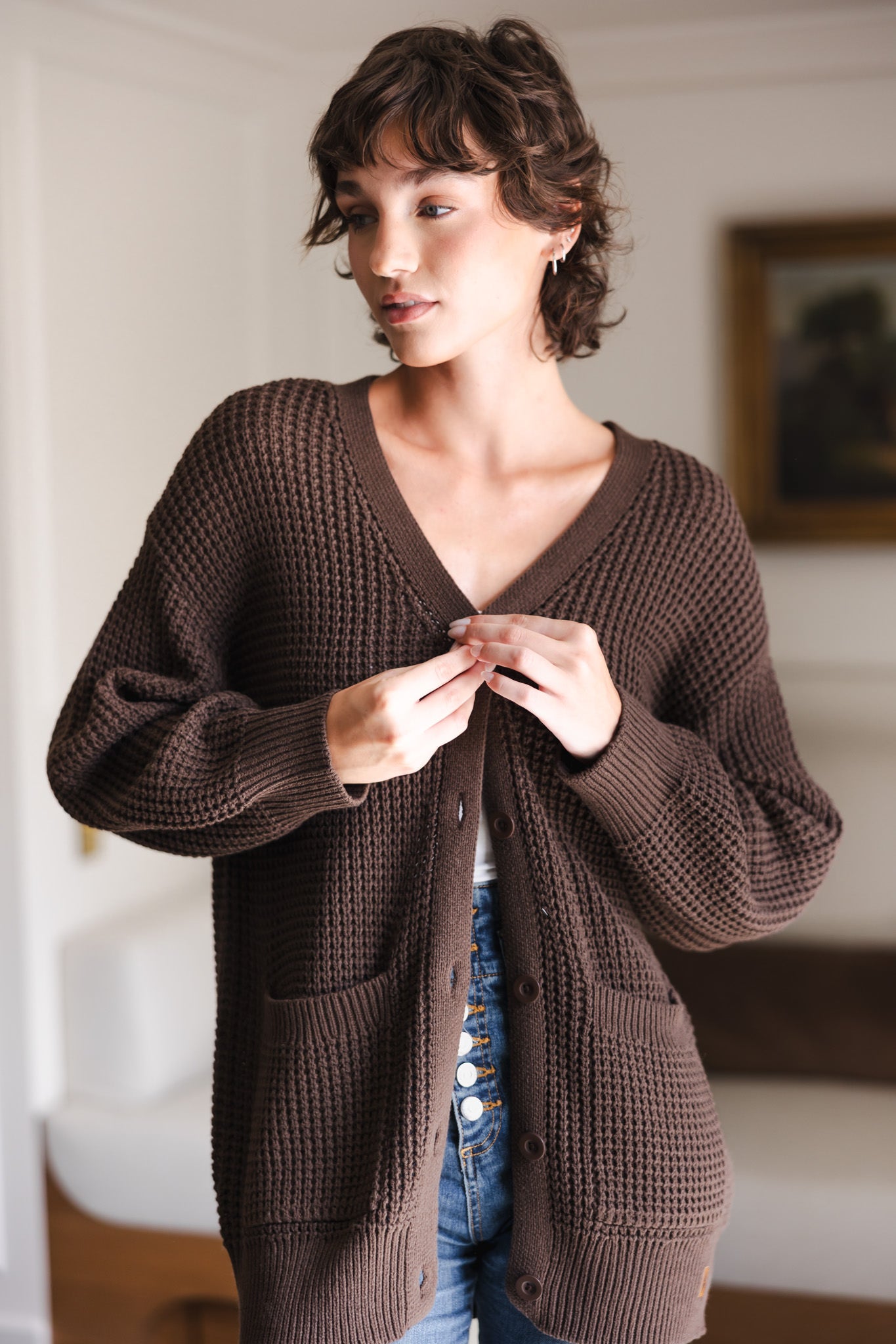 Modal buttoning the Chunky Knit Women's Waffle Cardigan in Espresso over white camisole and blue jeans
