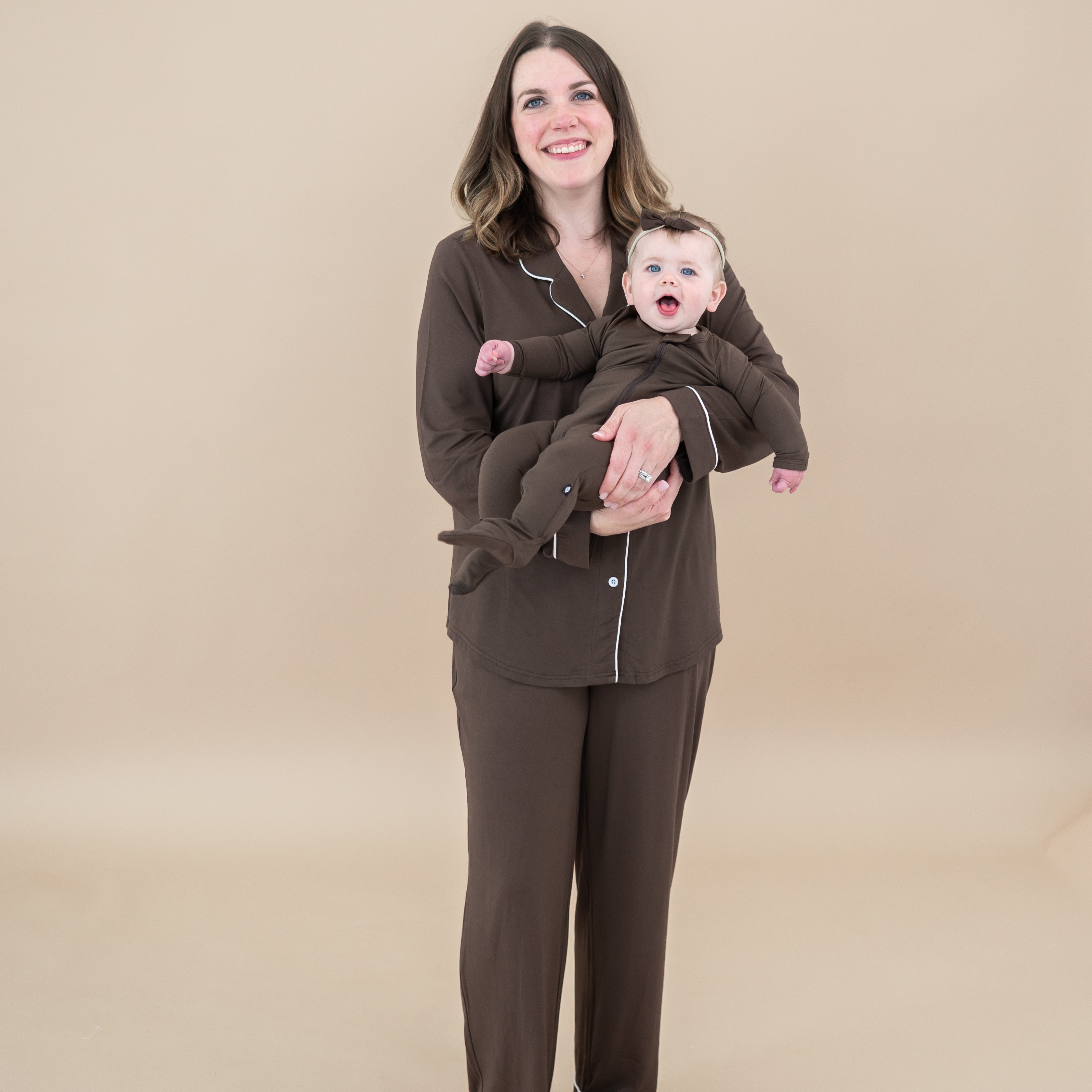 Female model wearing women's long sleeve pajama set matching her daughter who is in the Zippered Footie in Espresso