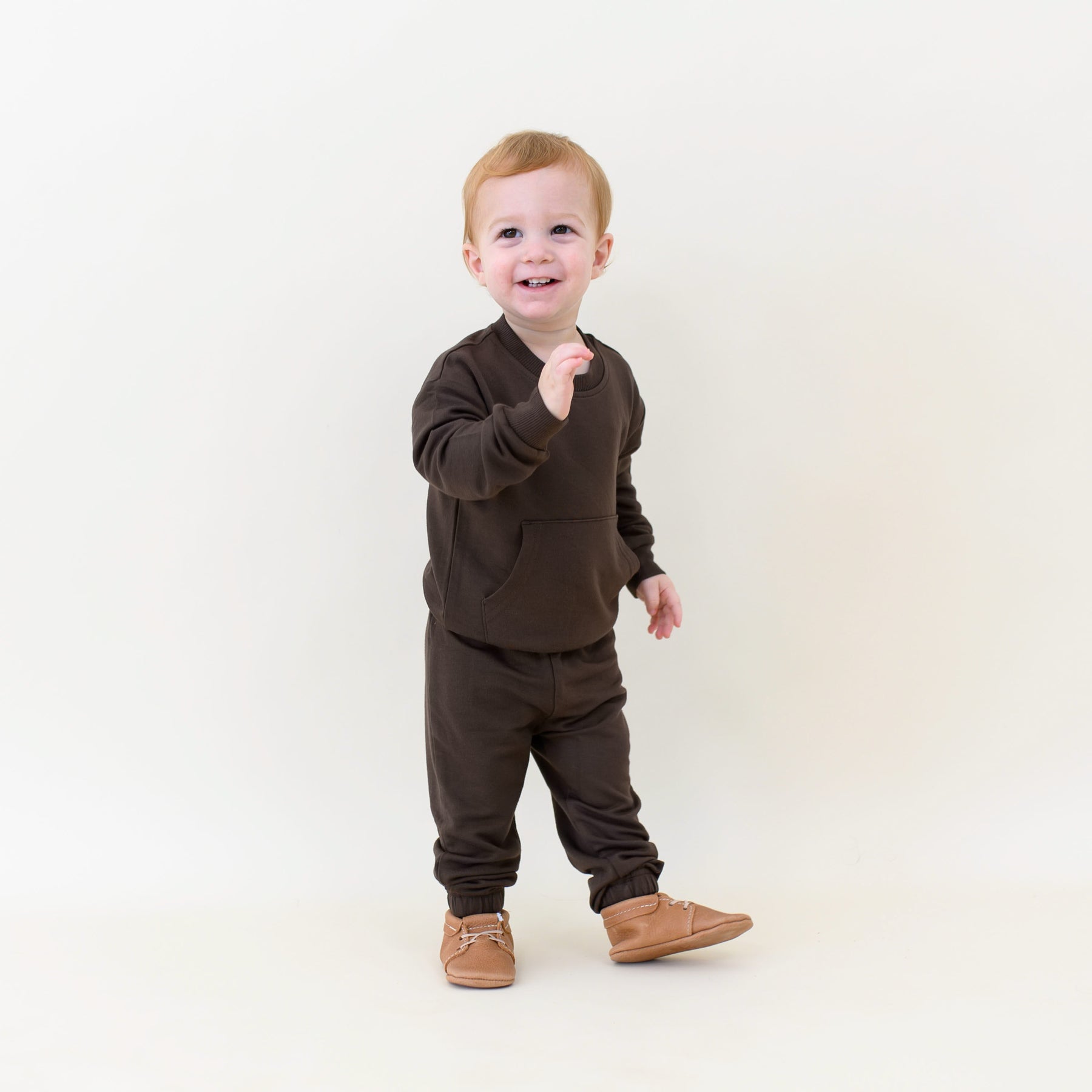Smiling toddler walking wearing the French Terry Jogger Set in Espresso