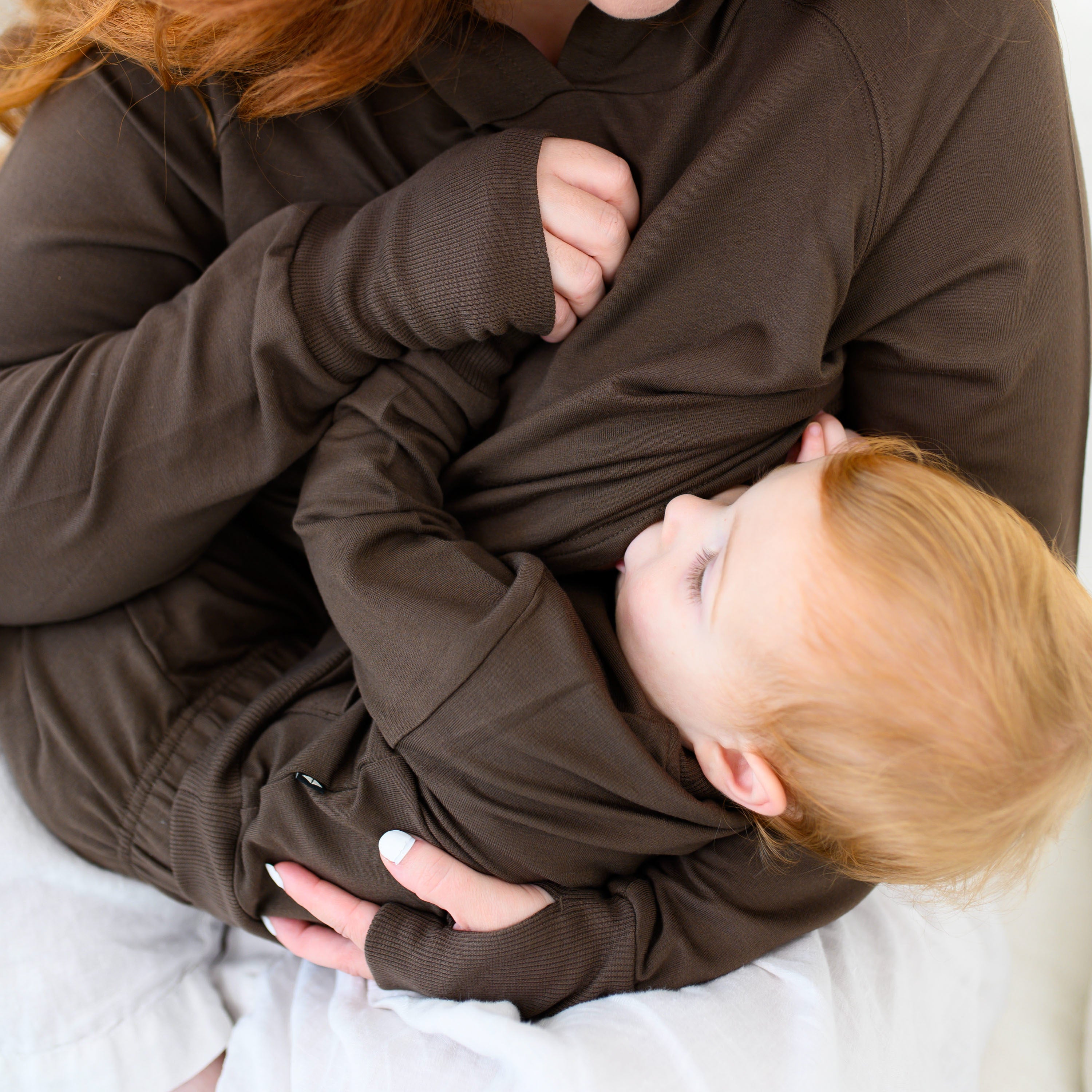 Mother wearing the Women's French Terry Nursing Hoodie in Espresso nursing her young toddler