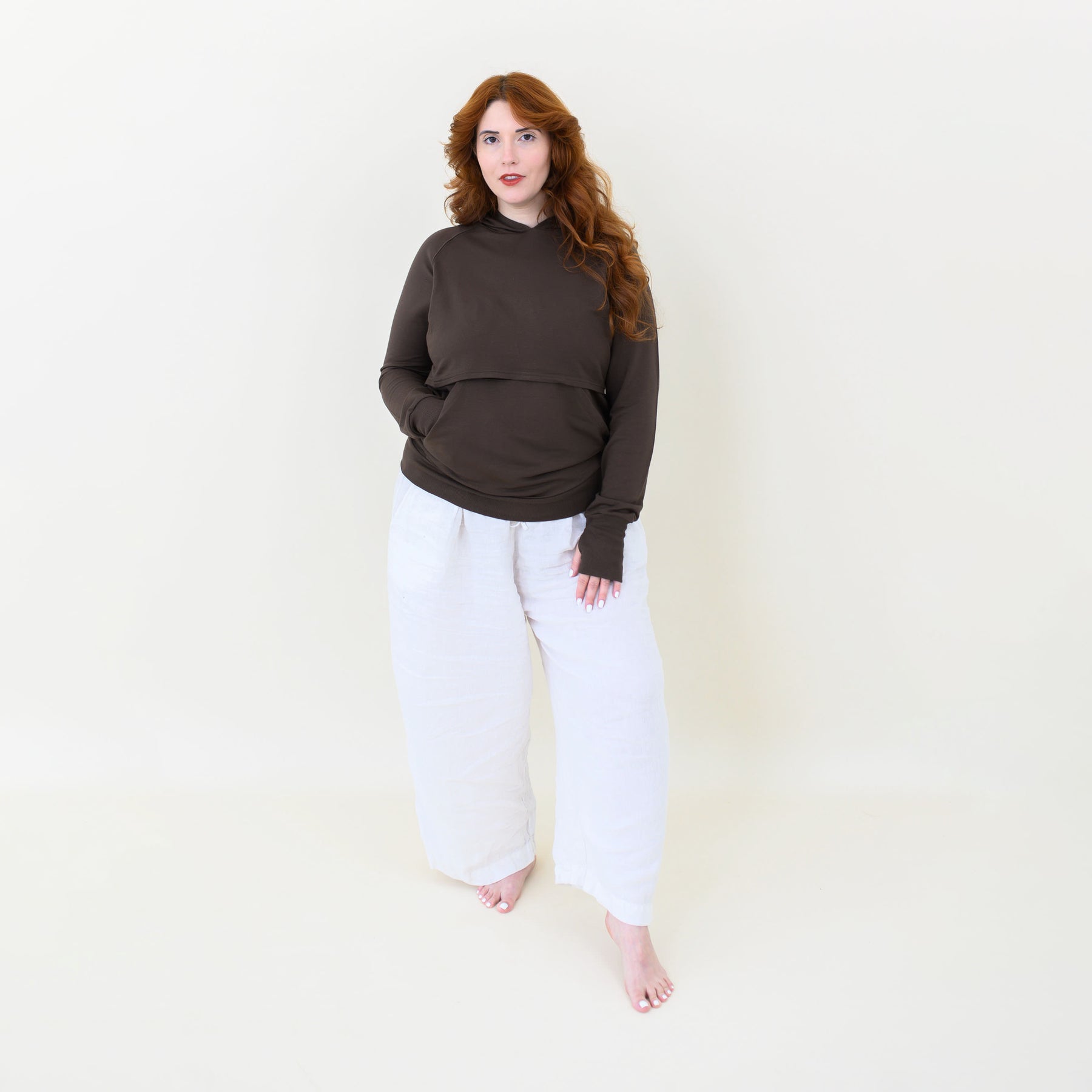 Female model wearing the Women's French Terry Nursing Hoodie in Espresso paired with white pants