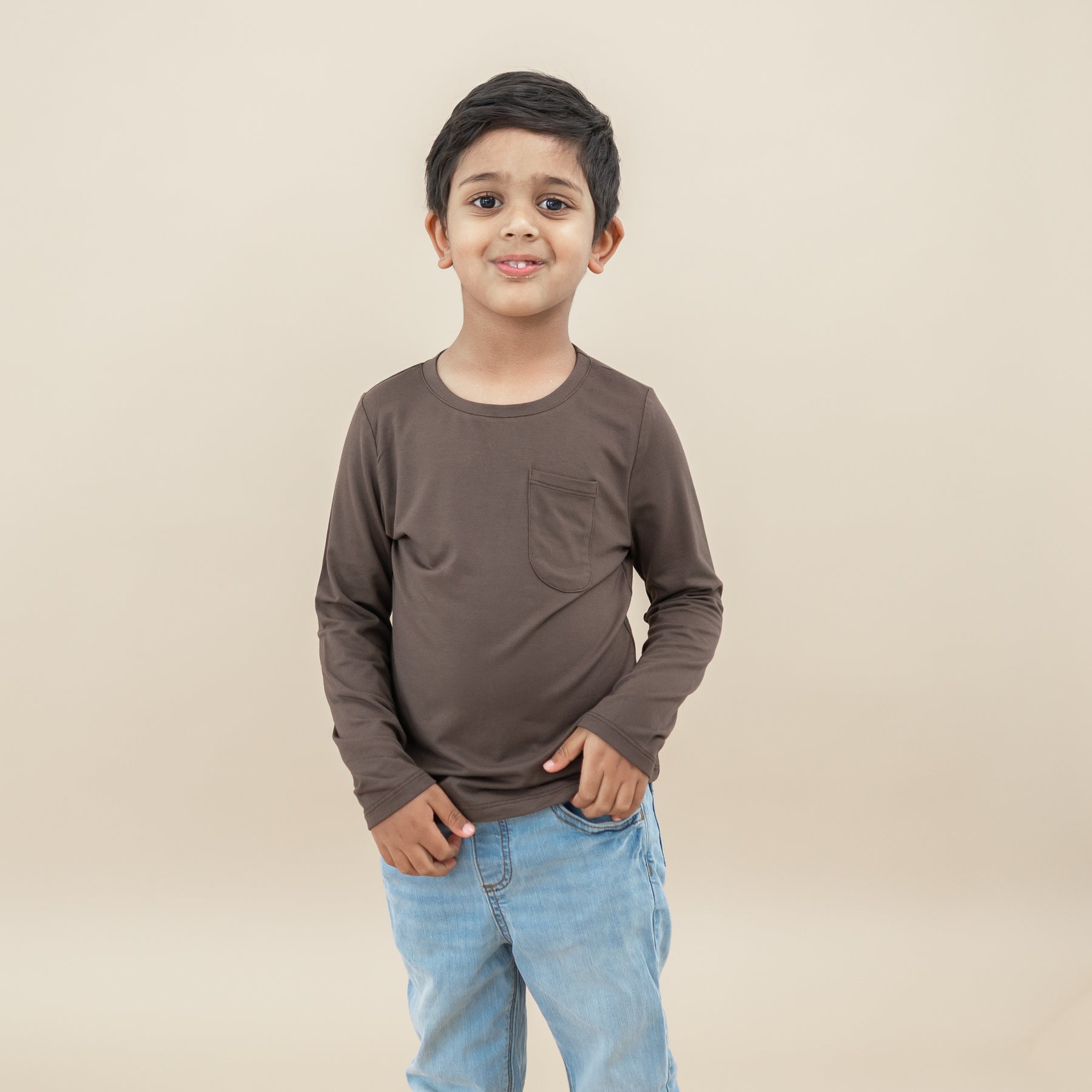 Boy model standing wearing the Long Sleeve Toddler Crew Neck Tee in Espresso paired with jeans