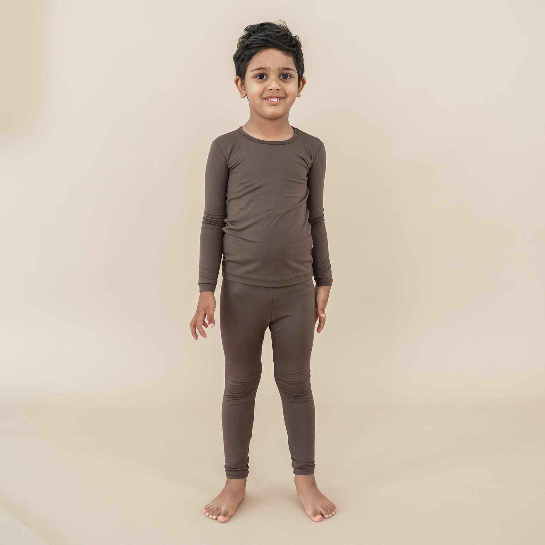 Boy model standing wearing the Long Sleeve Pajamas in Espresso