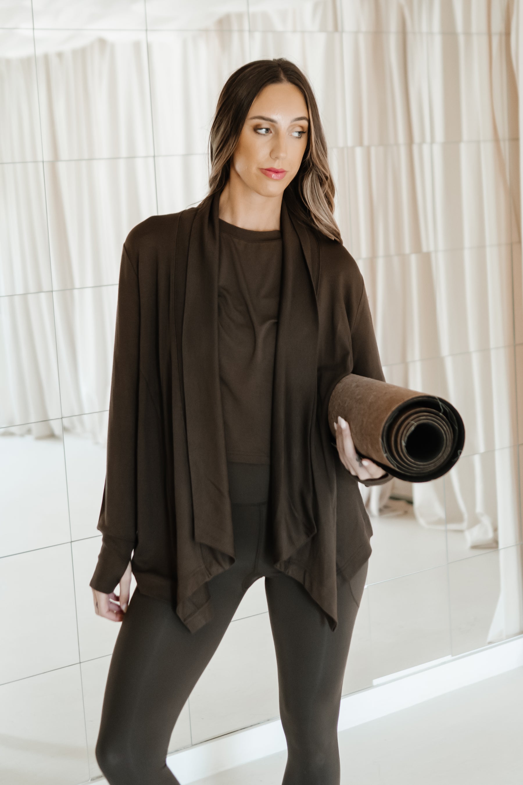 Female holding a yoga mat wearing the Bamboo Flex Women’s Leggings in Espresso and matching short sleeve tee and french terry wrap top