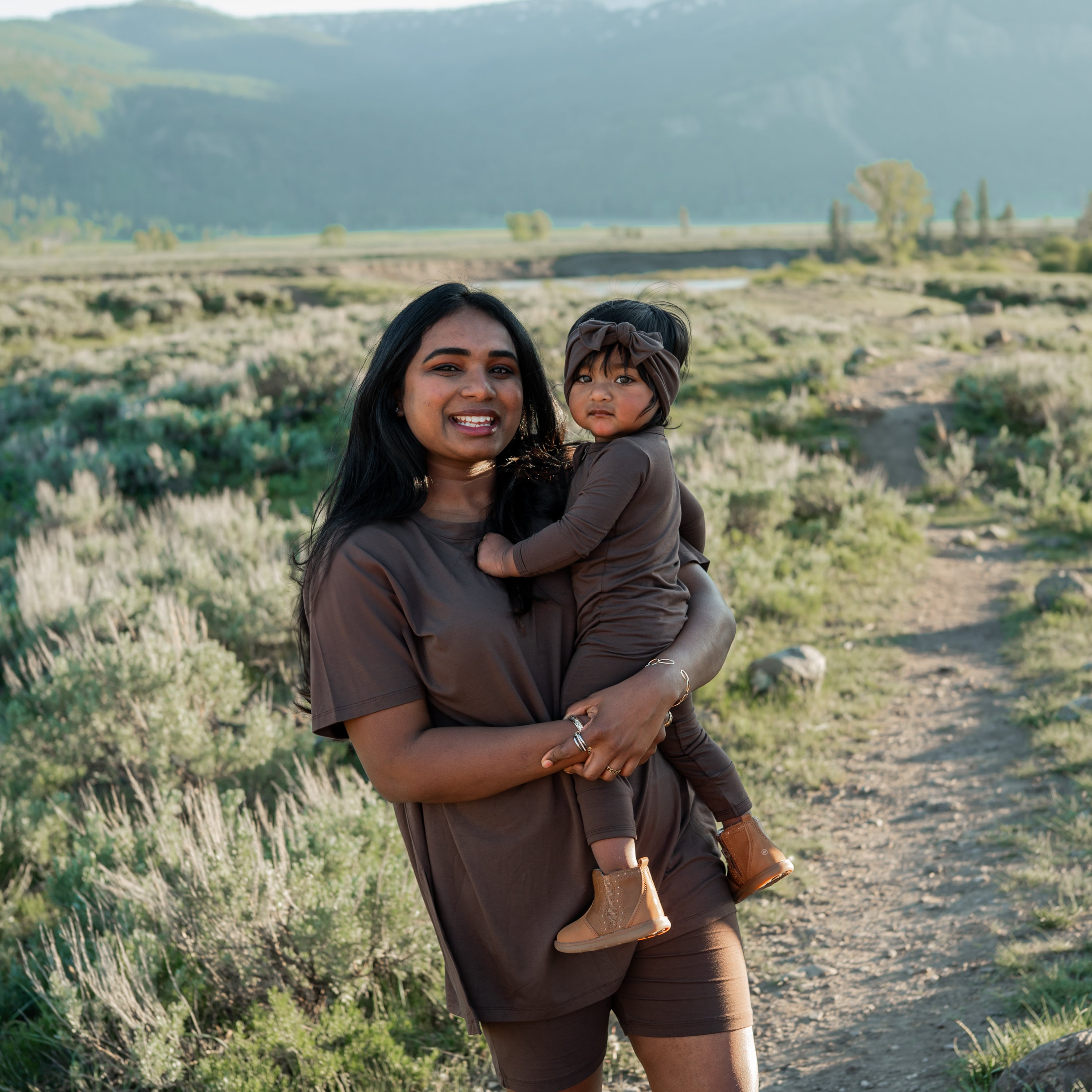 Mother and daughter matching in Espresso. Daughter wearing the Zippered Romper and mother wearing the Women's biker short set